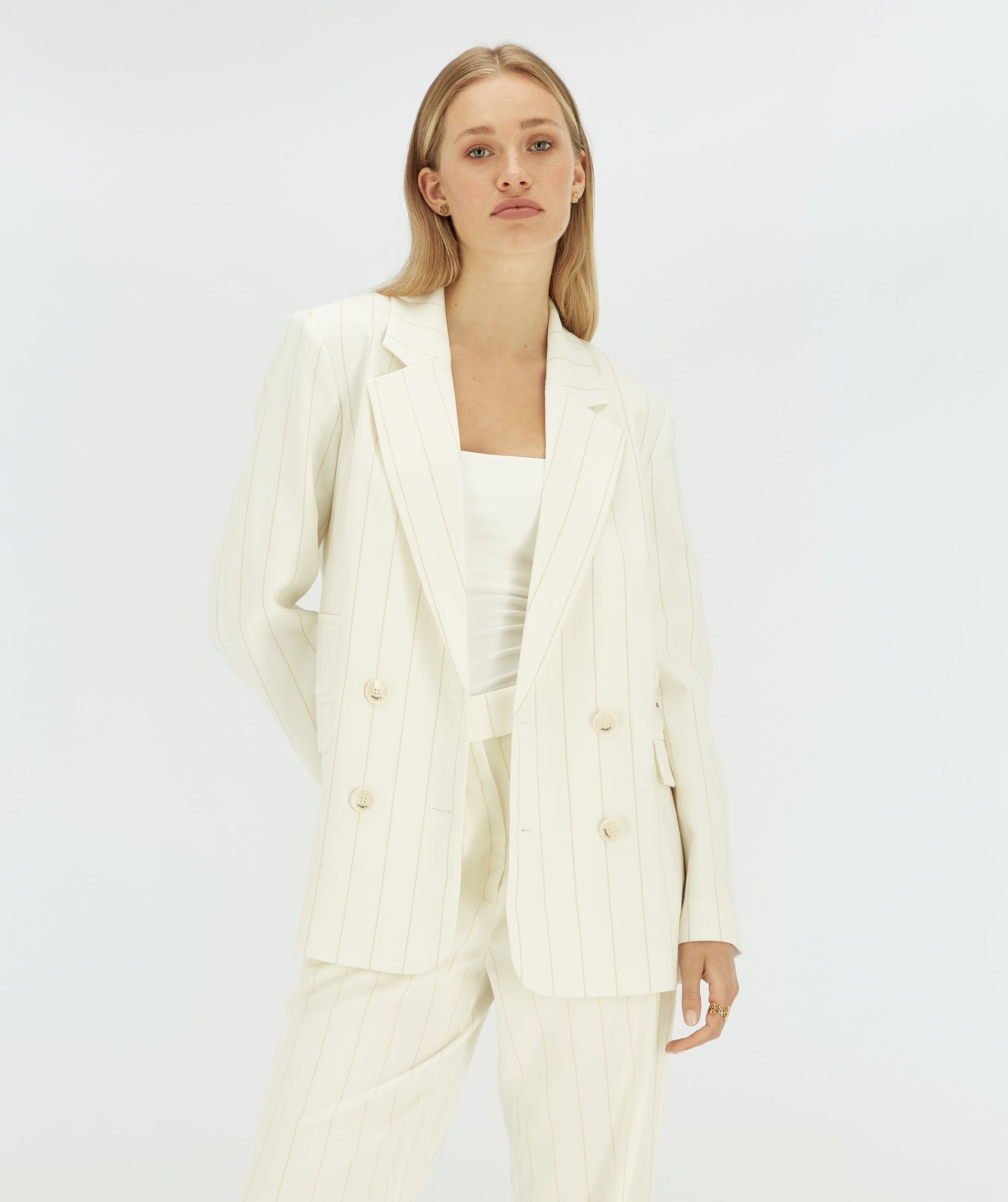 Model draagt een witte blazer met een beige krijtstreepje.