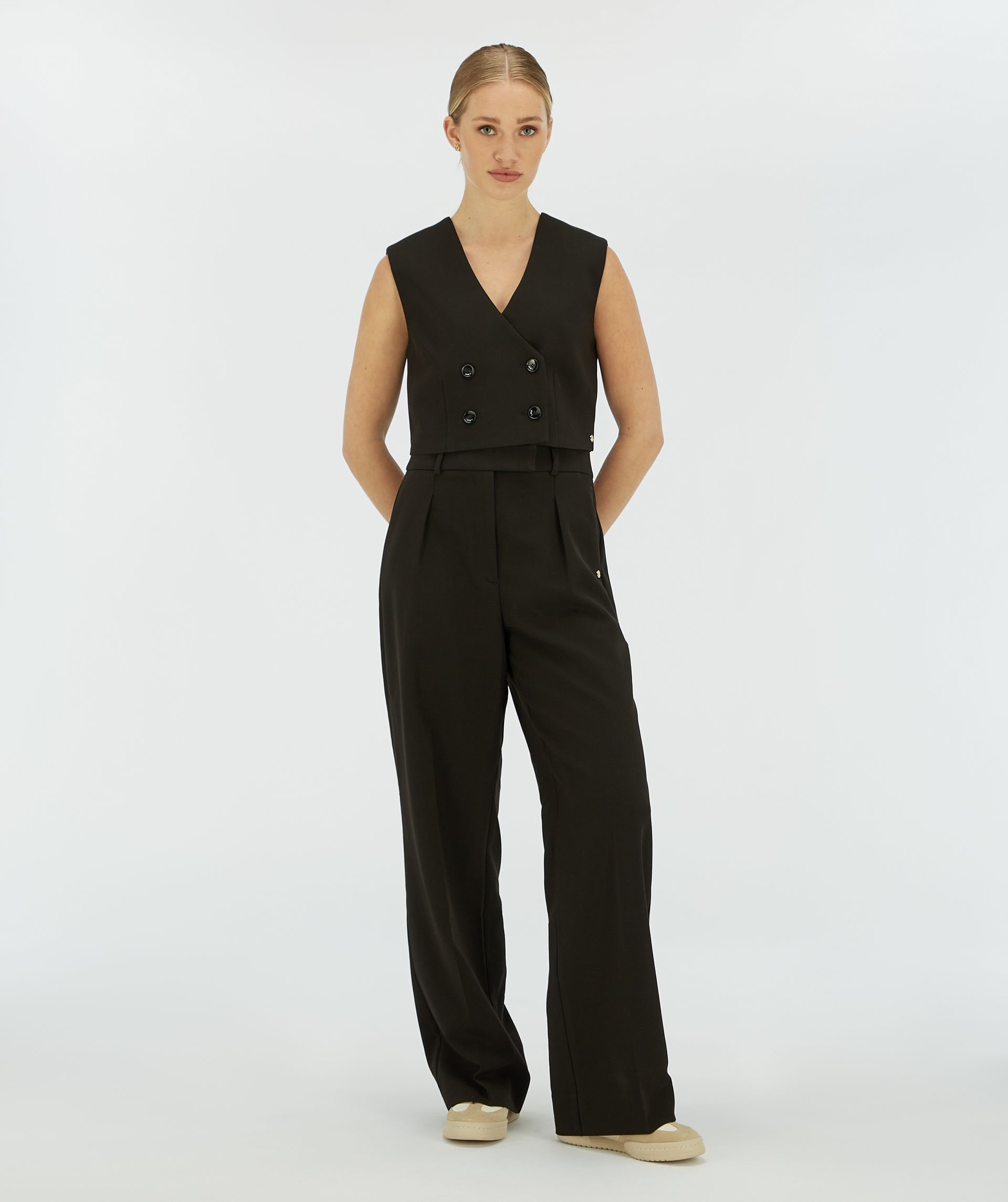 Model draagt een zwarte wide leg pantalon.