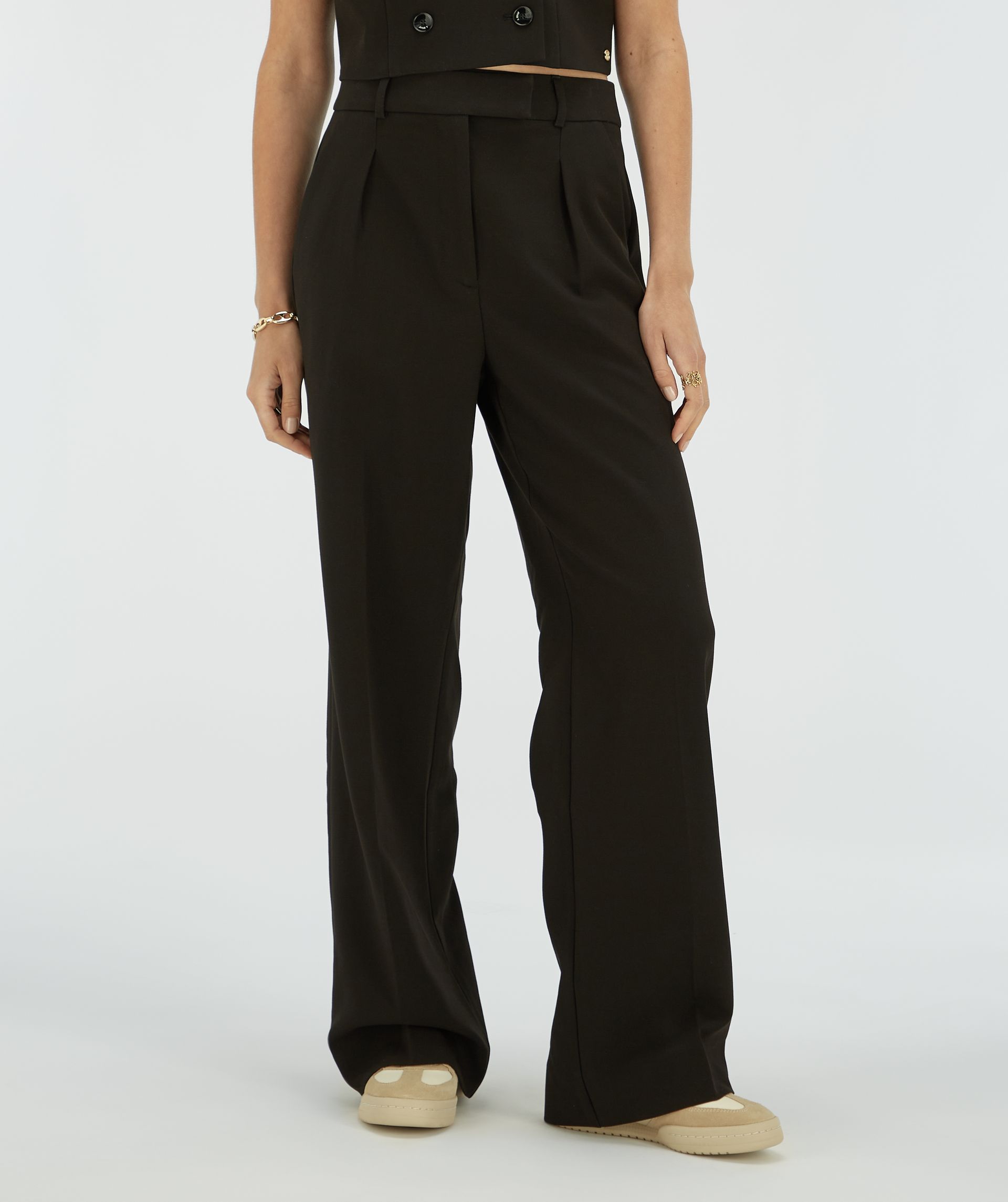 Model draagt een zwarte wide leg pantalon.