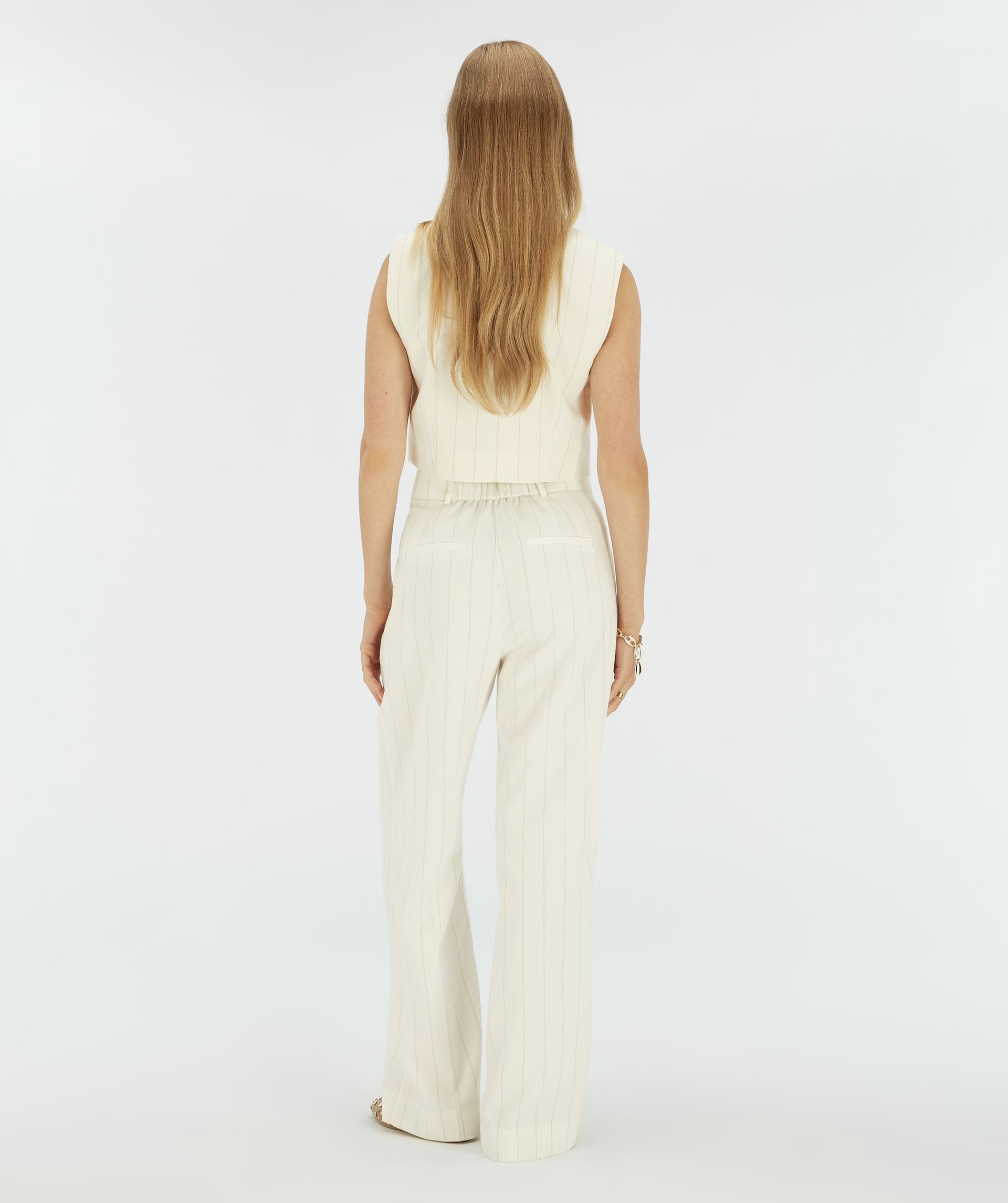 Achteraanzicht van een model in witte wide leg pantalon met beige krijtstreep.
