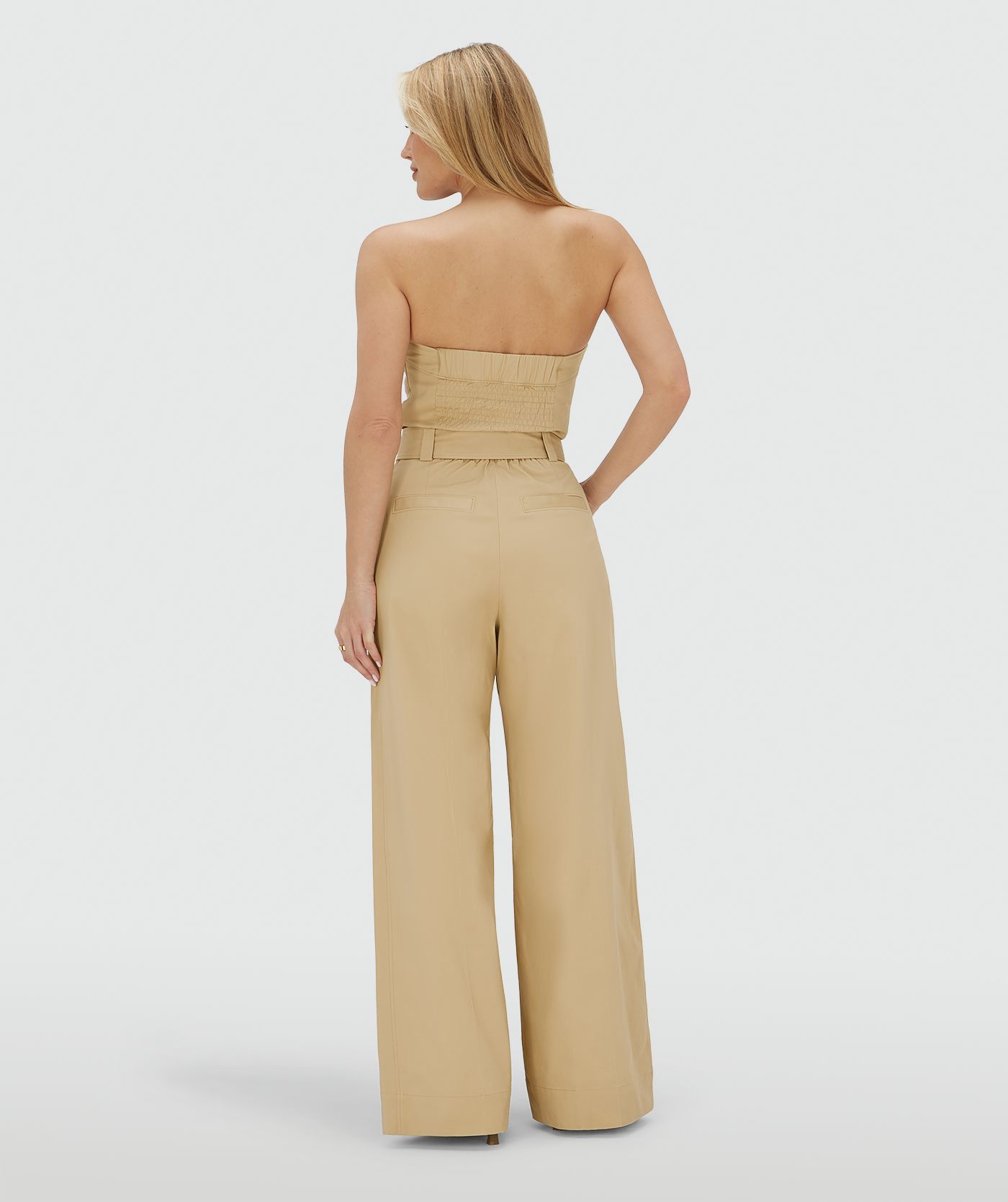 Achteraanzicht van een model in een wide leg jumpsuit in de kleur Light Camel met een gespdetail in de taille