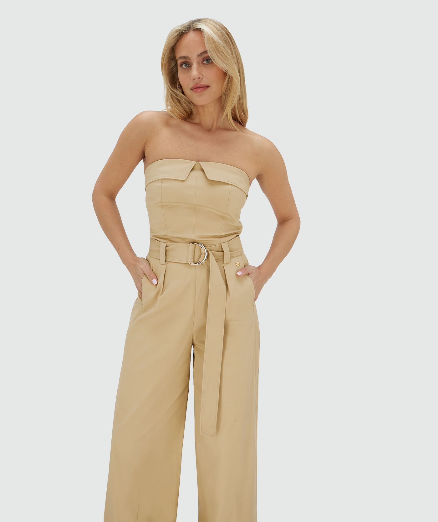 Model draagt een wide leg jumpsuit in de kleur Light Camel met een gespdetail in de taille