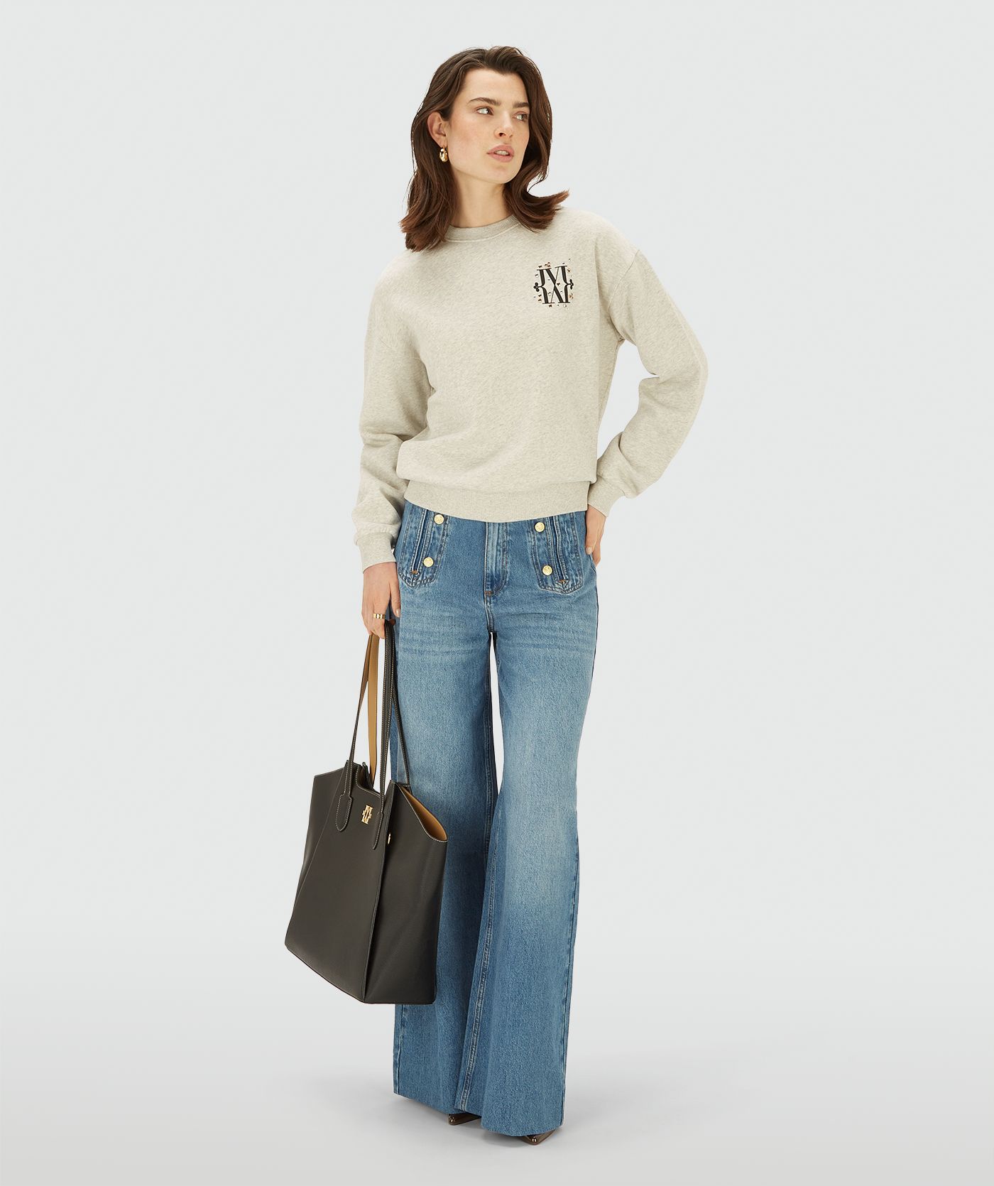 Model draagt een Salt Melange sweater met ronde hals en een subtiel JOSH V-logo op de borst, afgewerkt met kleine glanzende details