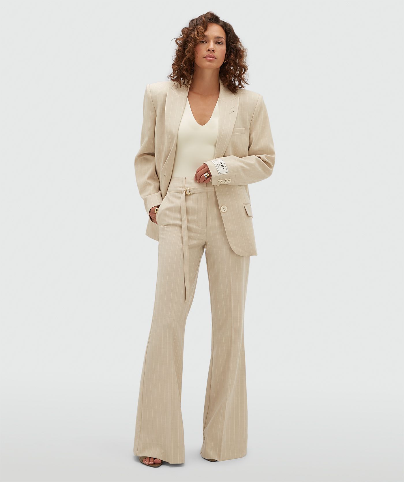 Model draagt een oversized beige blazer met krijtstreepje.