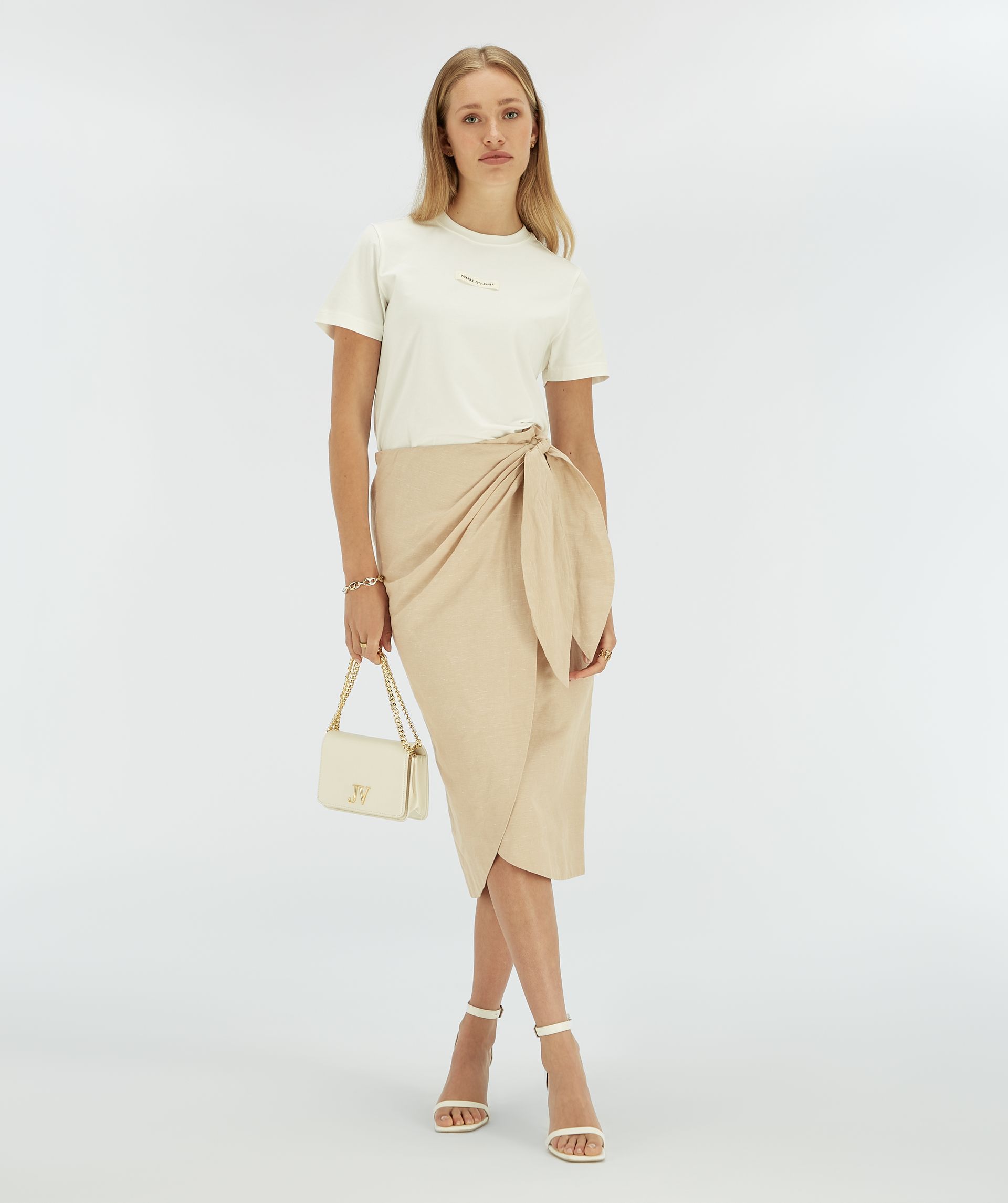 Model draagt een beige overslagrok met striksluiting.