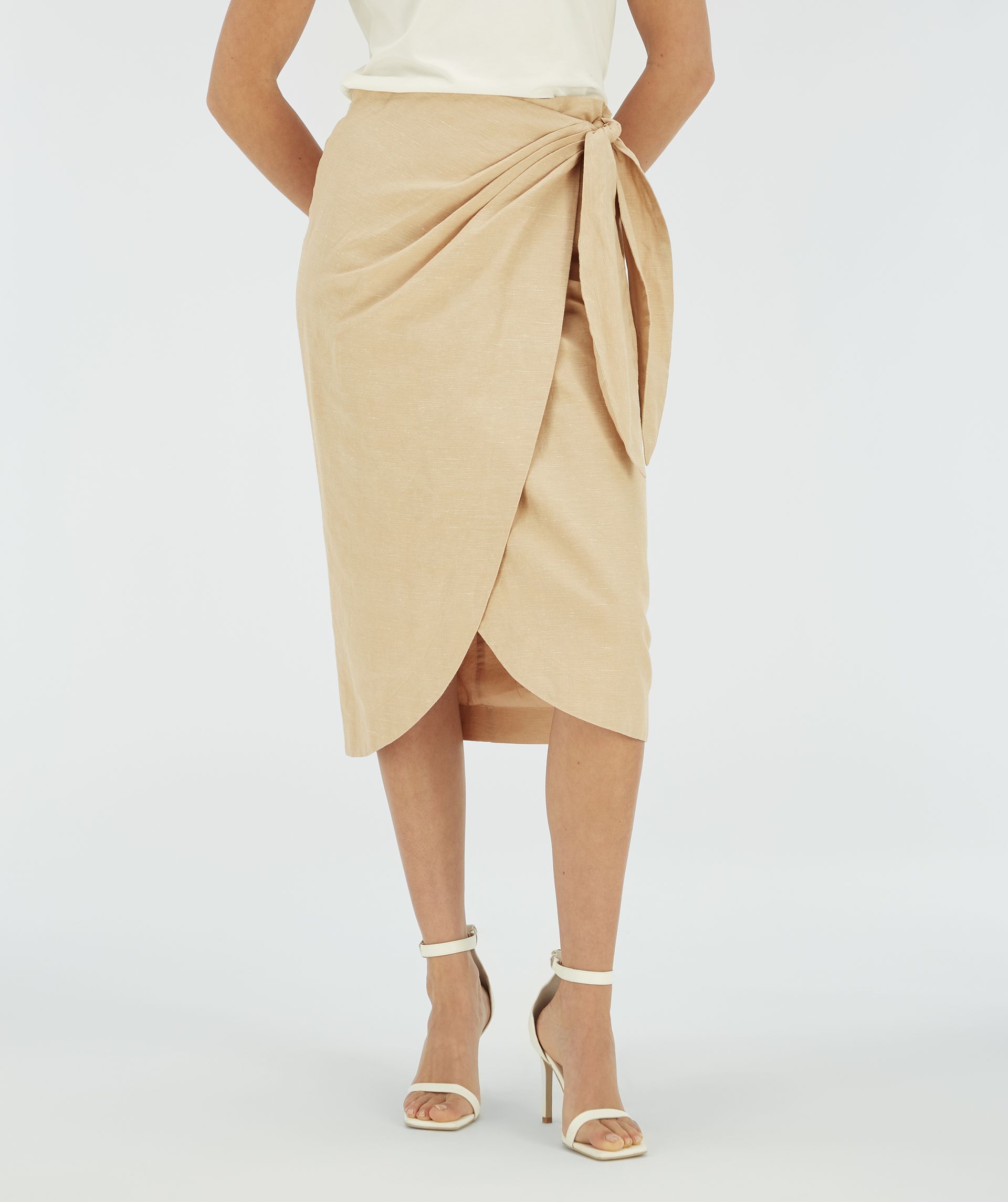 Model draagt een beige overslagrok met striksluiting.