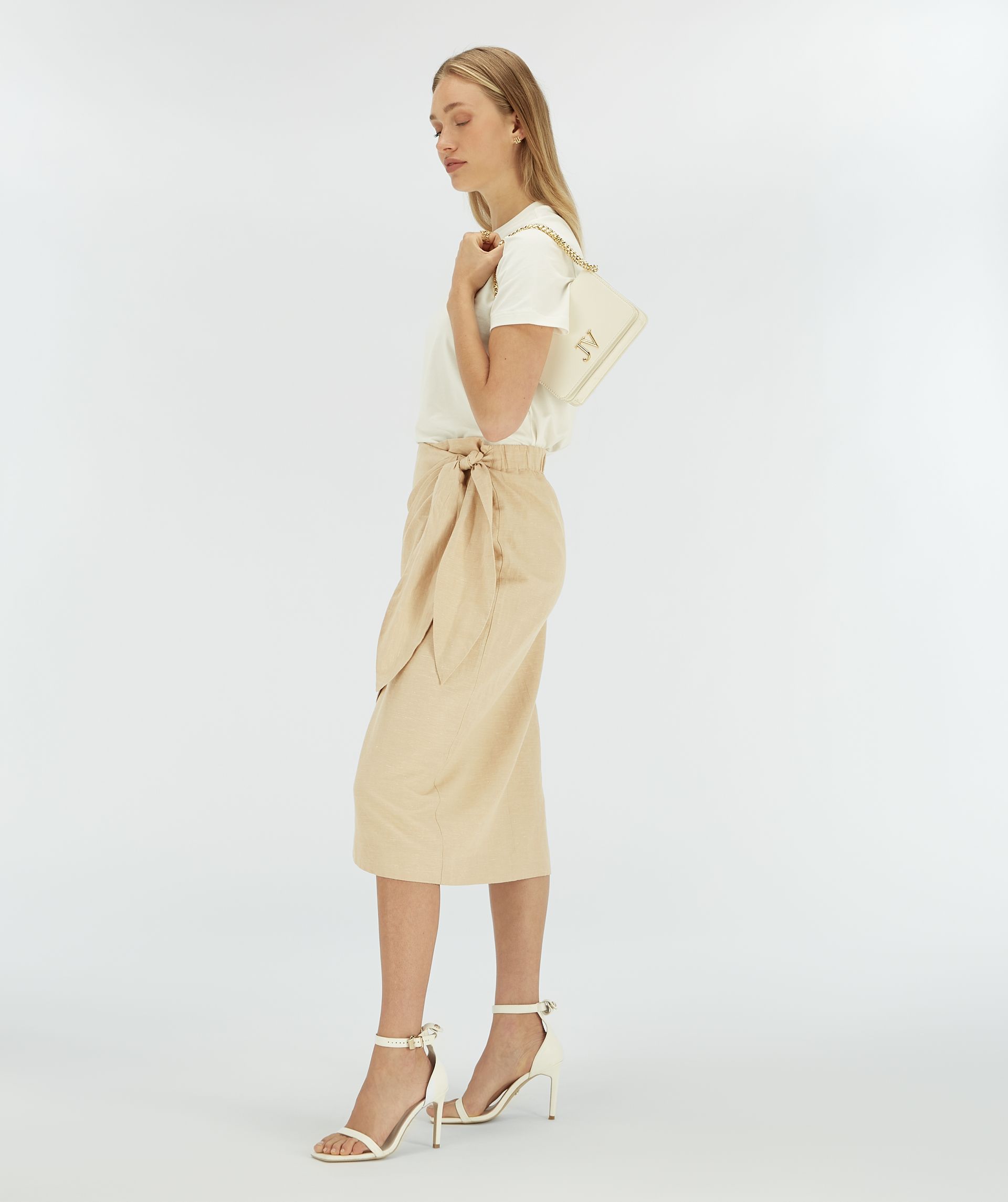 Model van opzij in een beige overslagrok.