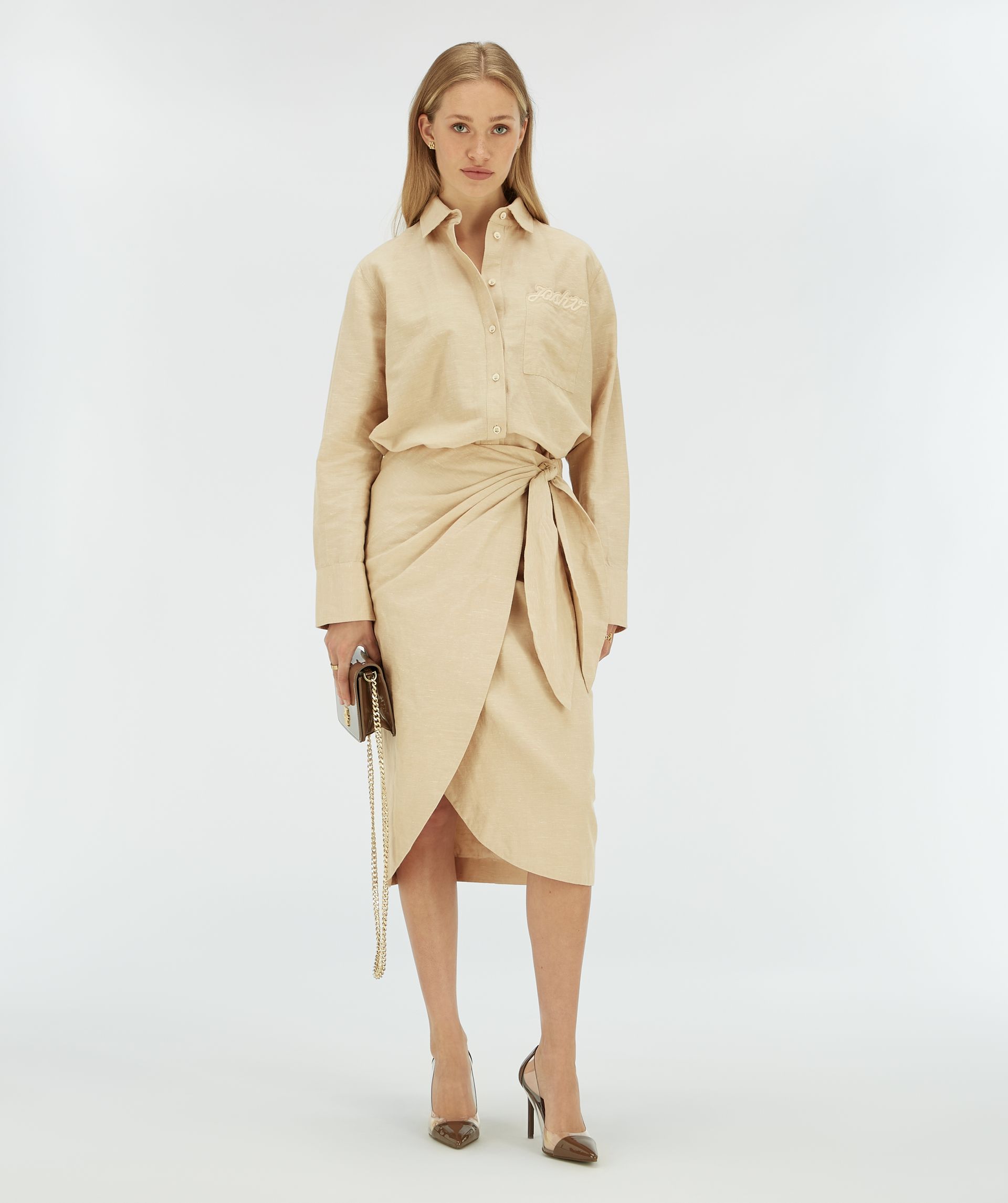 Model draagt een beige overslagrok met striksluiting.
