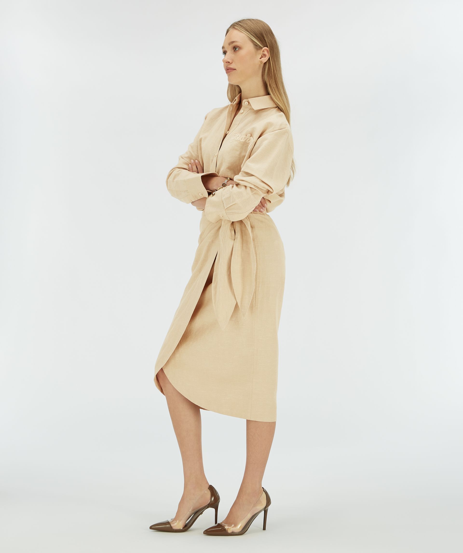Model van opzij in een beige overslagrok.