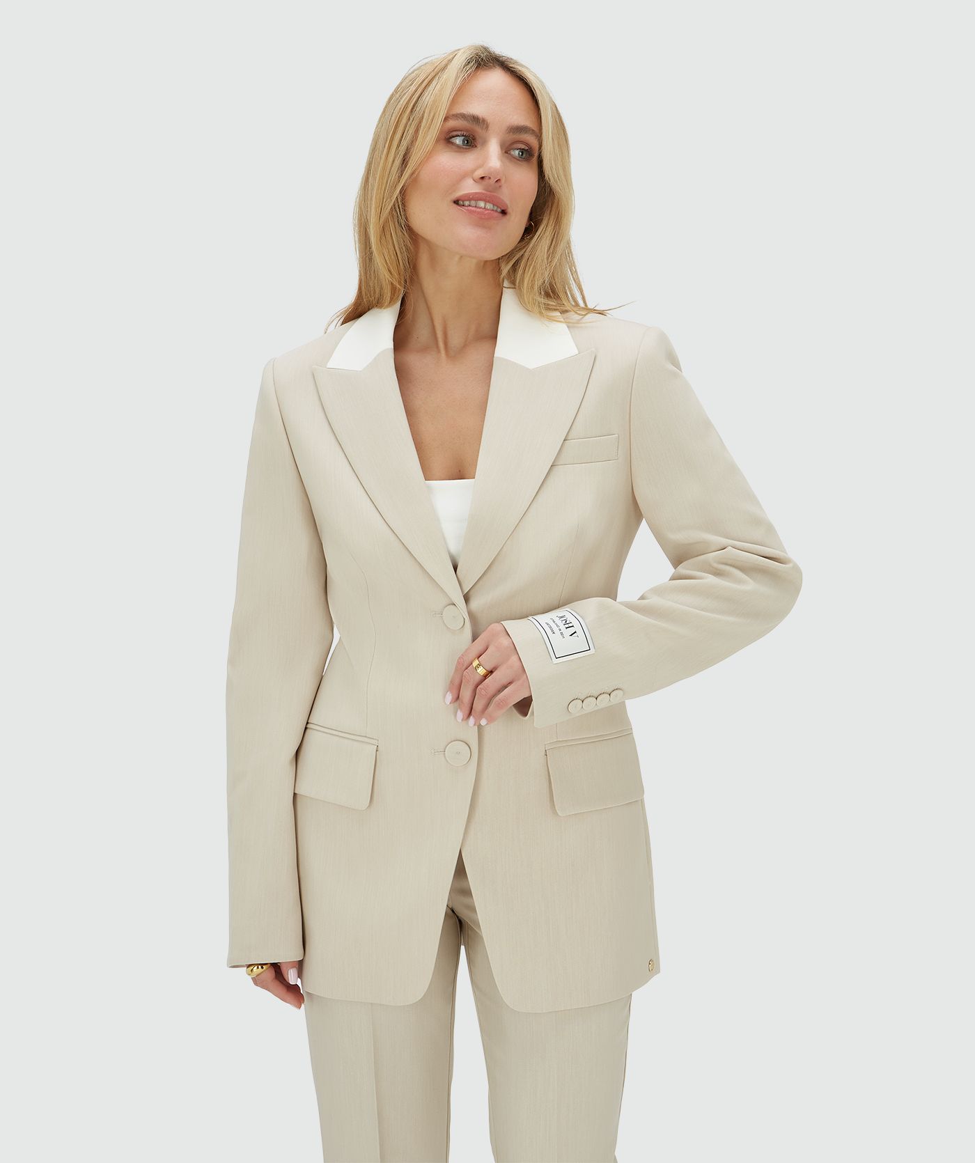 Het model draagt een fitted blazer in de kleur Ecru Melange, waarbij de kraag is uitgevoerd in ecru en de rest van de blazer in melange. Op de mouw is het JOSH V-label te zien