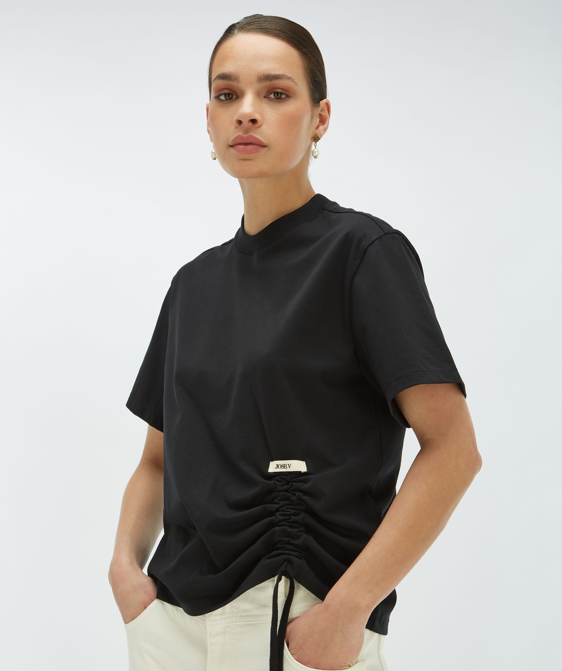 Model draagt een zwart regular fit T-shirt met een trekkoordaccent aan de linkeronderkant - Josh V.