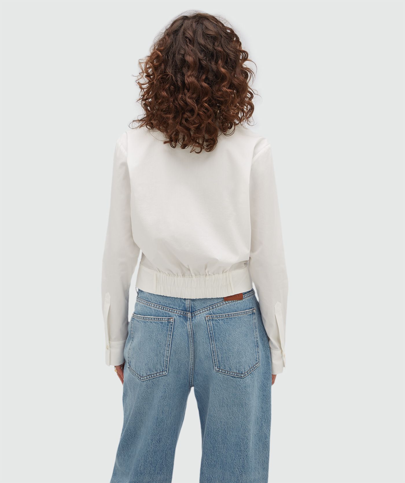 Achteraanzicht van een model in een witte blouse.