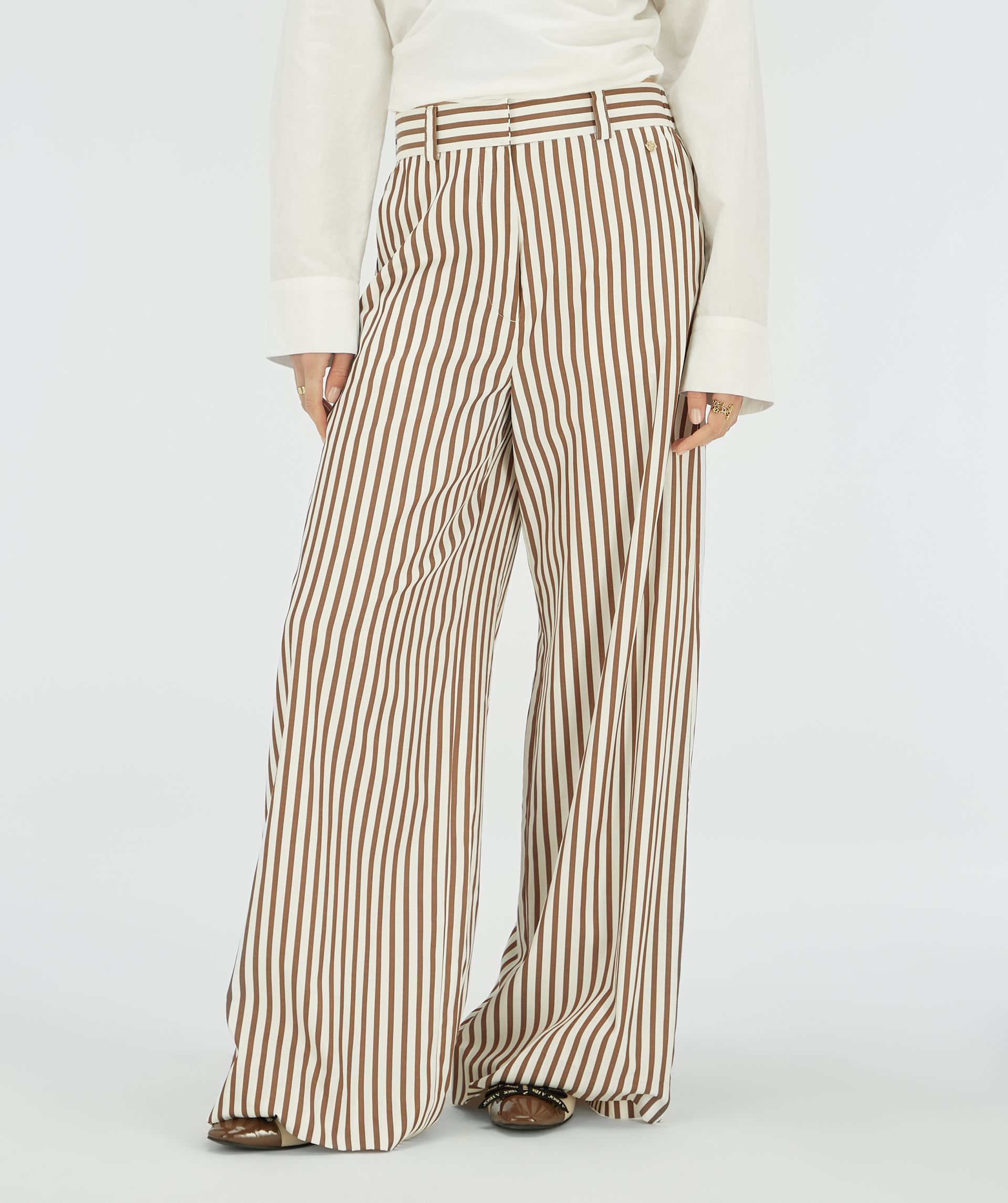 Model draagt een bruin wit gestreepte wide leg broek,.