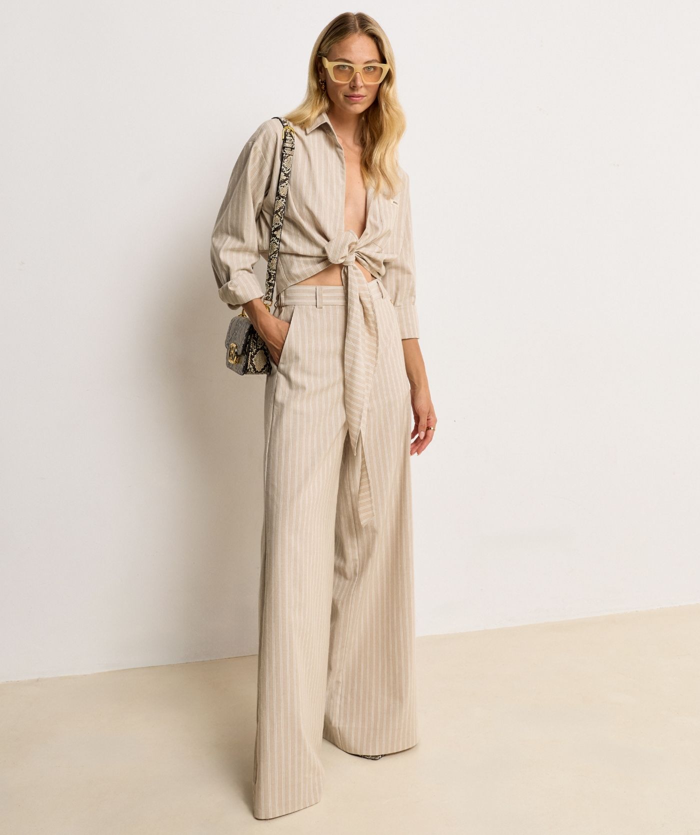 Model draagt een mid rise wide leg pantalon met strepen in de kleur Stone Stripe