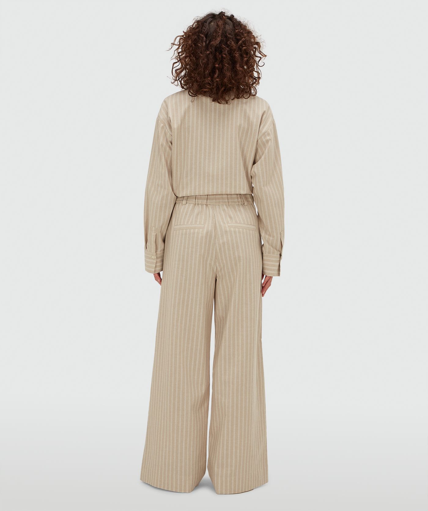 Achteraanzicht van een model in een mid rise wide leg pantalon met strepen in de kleur Stone Stripe