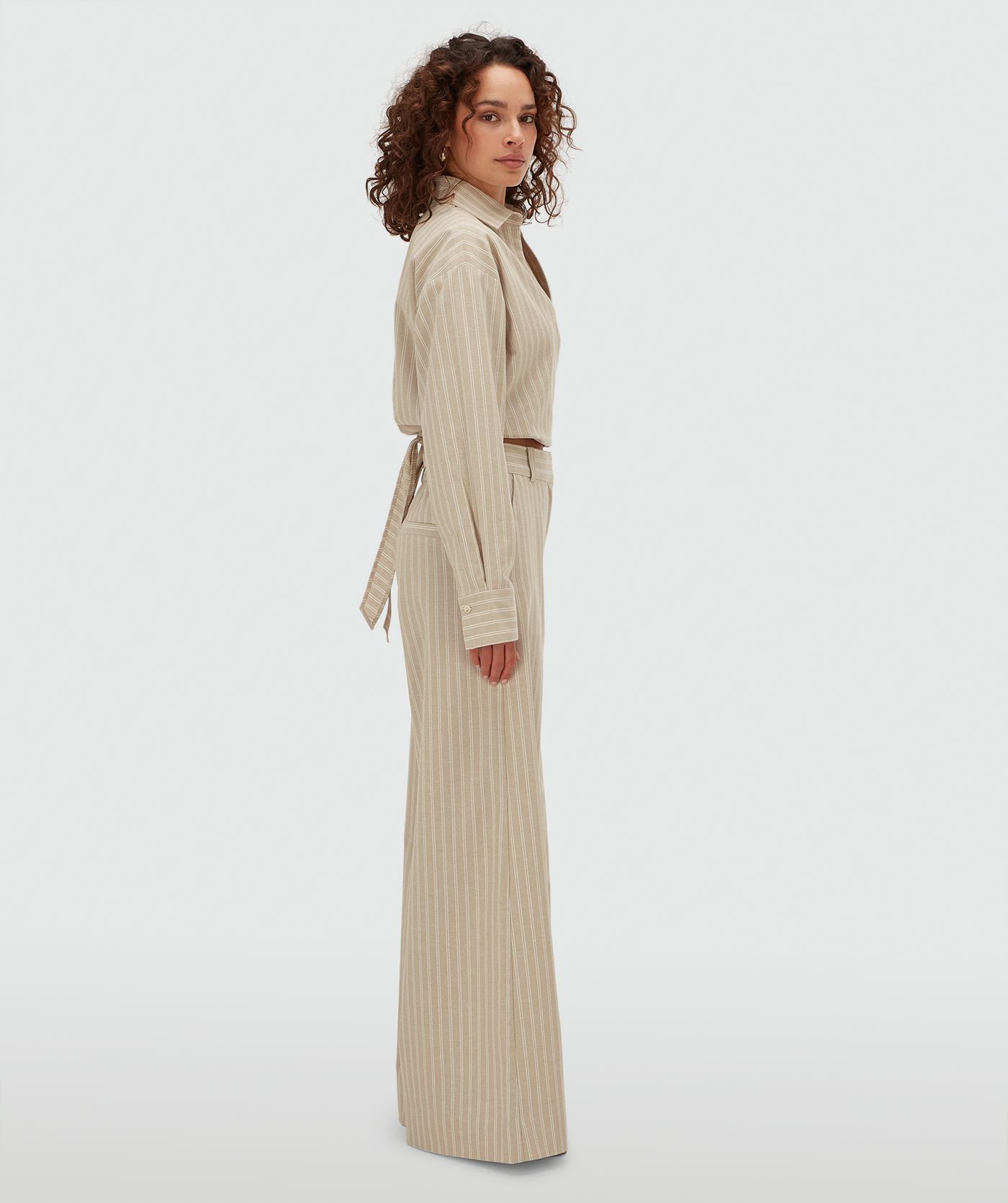 Zijaanzicht van een model in een mid rise wide leg pantalon met strepen in de kleur Stone Stripe
