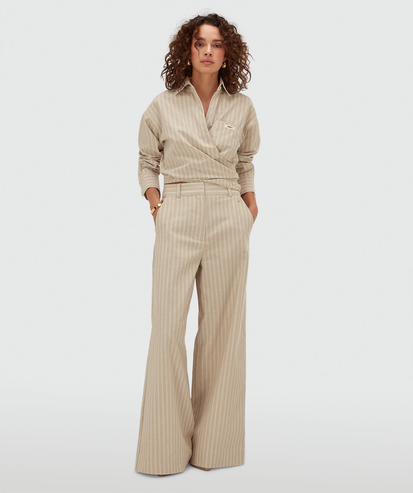 Model draagt een mid rise wide leg pantalon met strepen in de kleur Stone Stripe