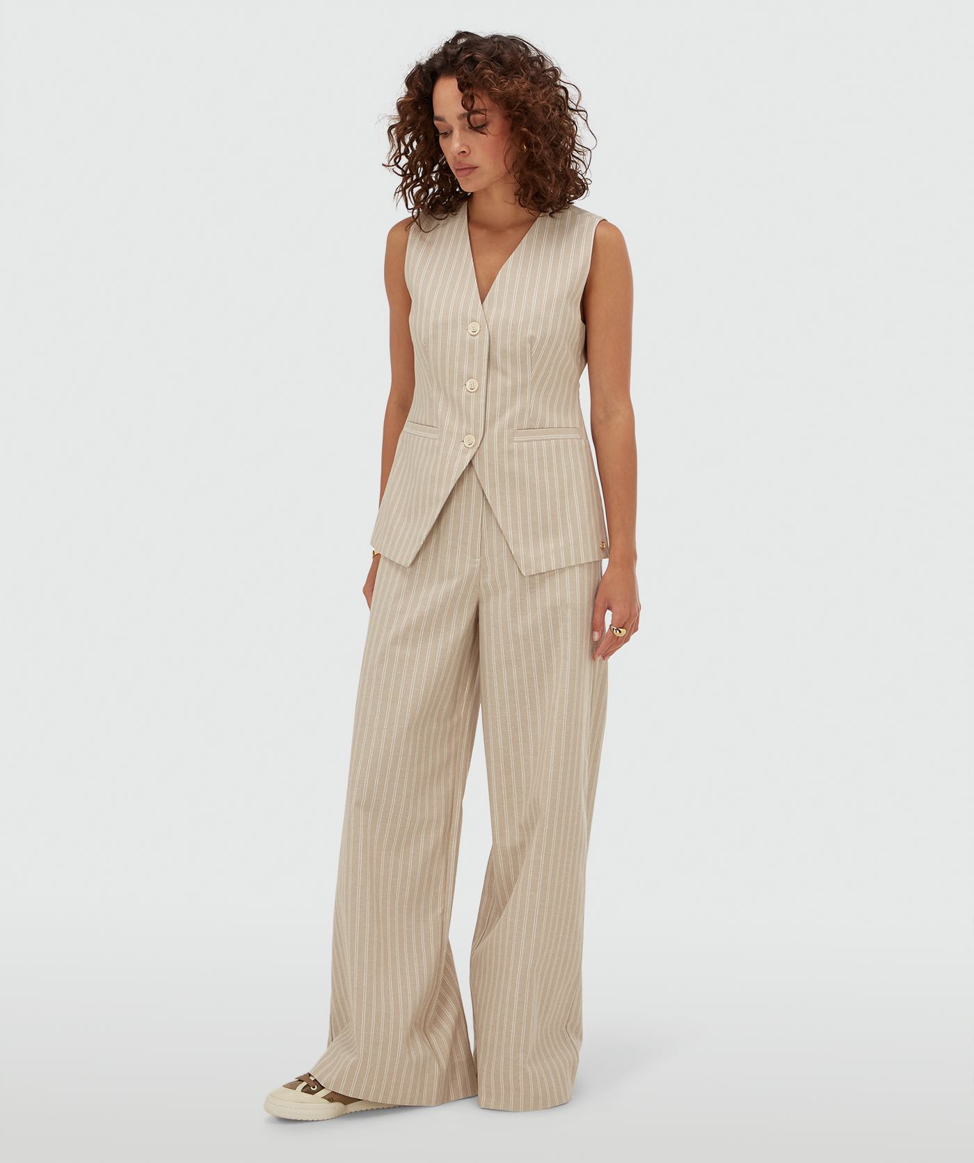 Model draagt een mid rise wide leg pantalon met strepen in de kleur Stone Stripe