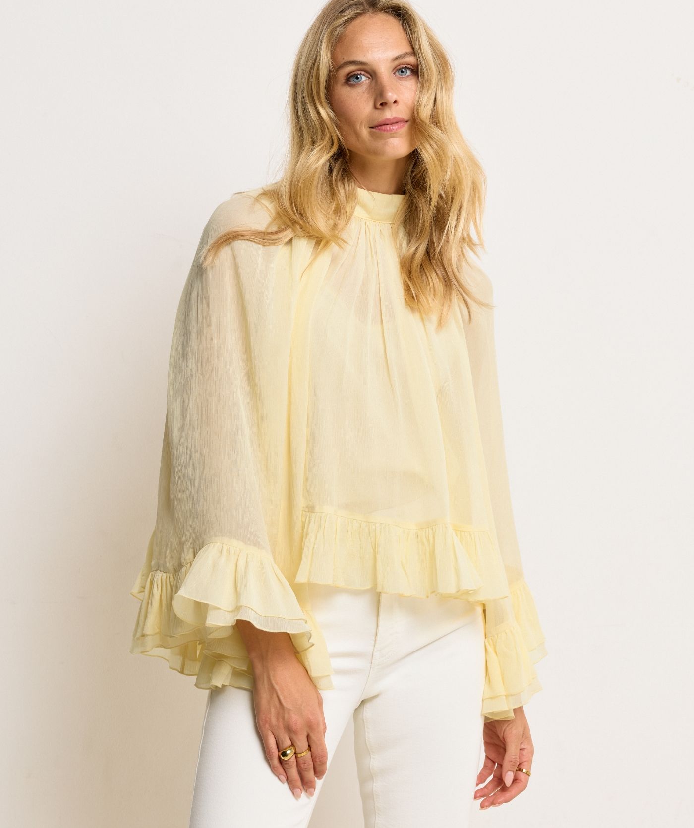 Model draagt een oversized top met ruffle details in de kleur Butter Yellow