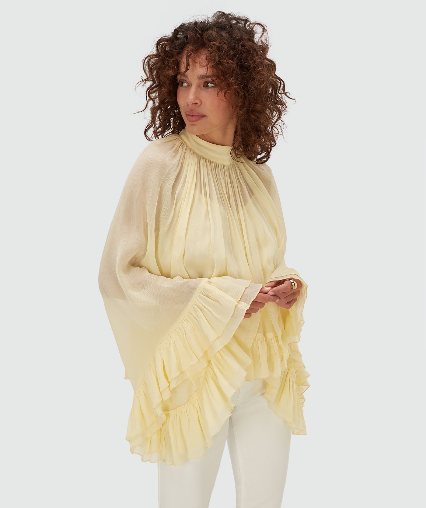 Model draagt een oversized top met ruffle details in de kleur Butter Yellow