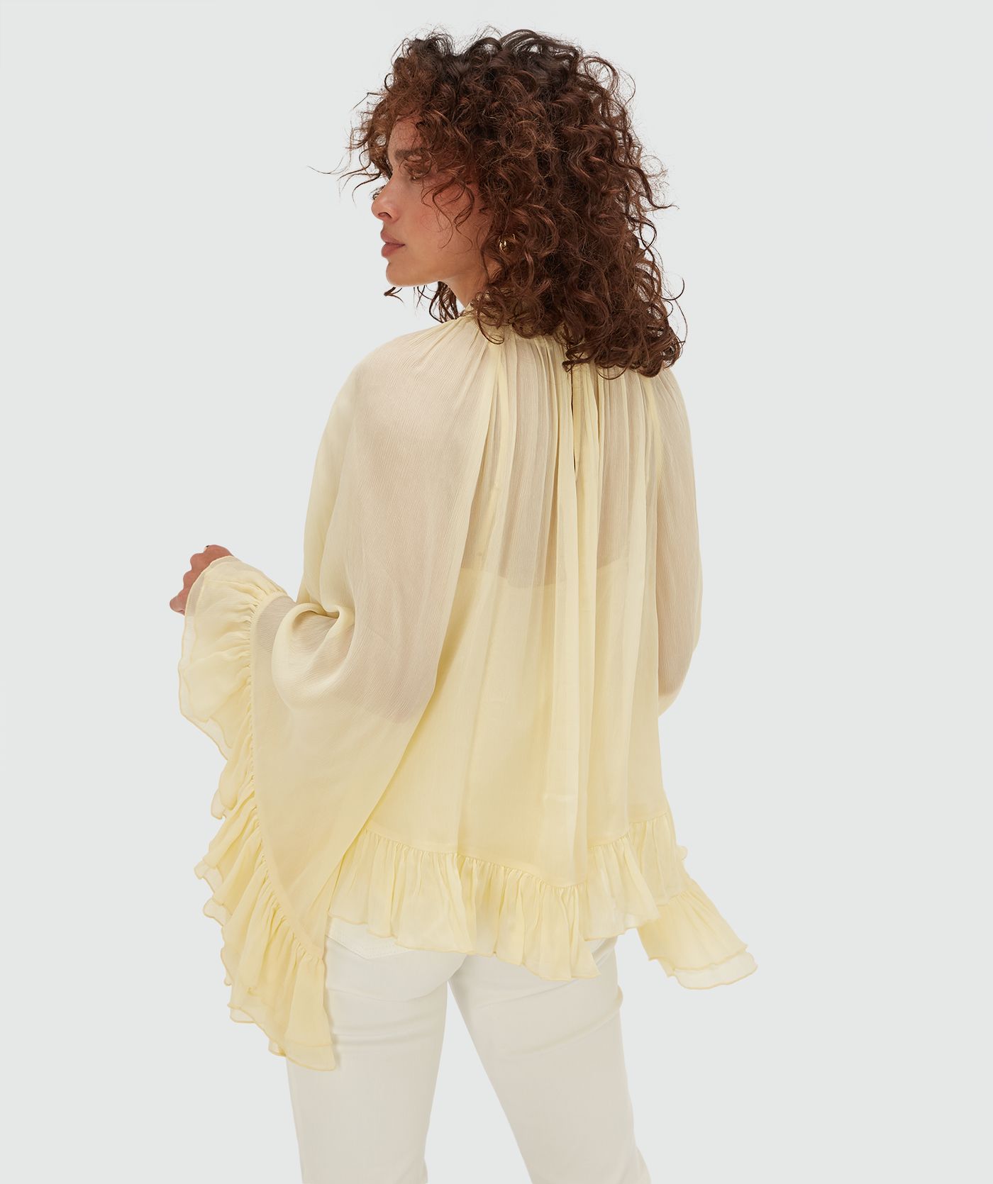 Achterzijde van een model in een oversized top met ruffle details in de kleur Butter Yellow