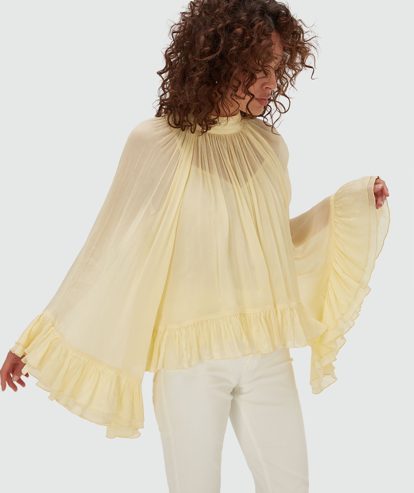 Model draagt een oversized top met ruffle details in de kleur Butter Yellow