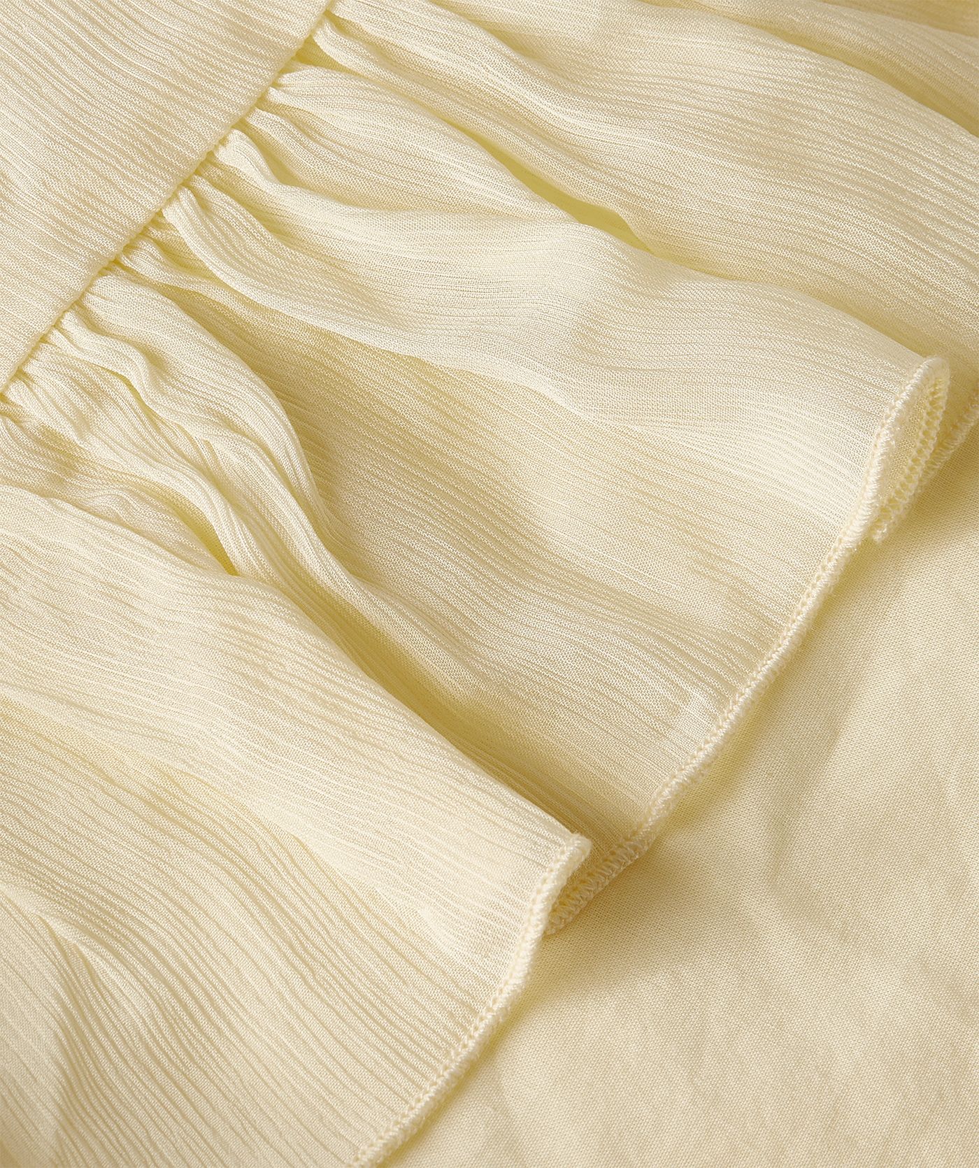 Close-up van een oversized top met ruffle details in de kleur Butter Yellow