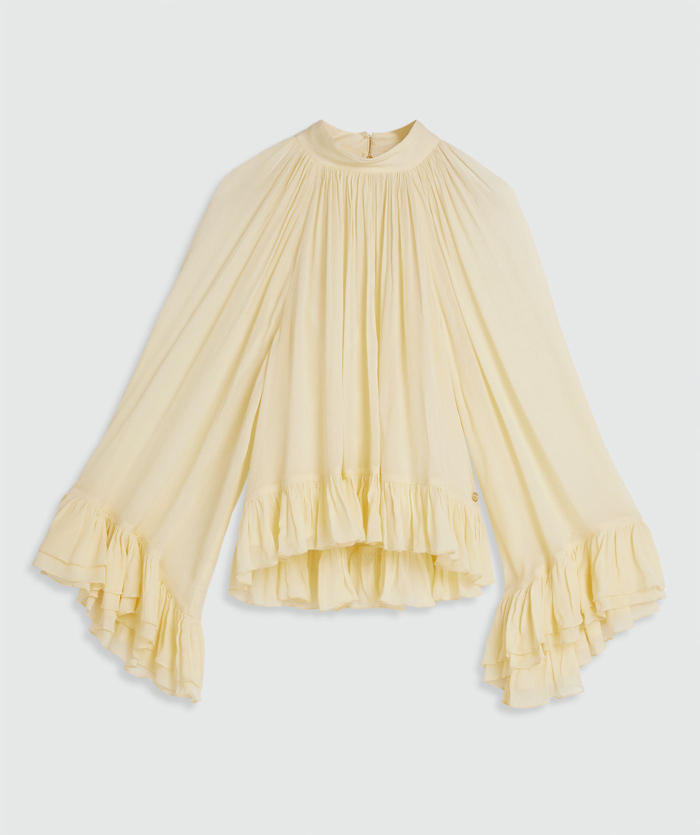 Een oversized top met ruffle details in de kleur Butter Yellow, zonder model, weergegeven op een lichtgrijze achtergrond