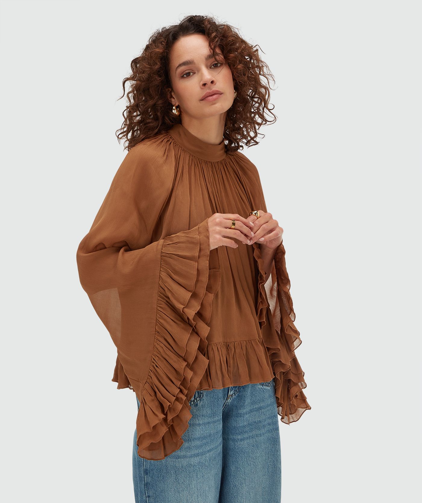 Model draagt een oversized top met ruffle details in de kleur Mocha Brown
