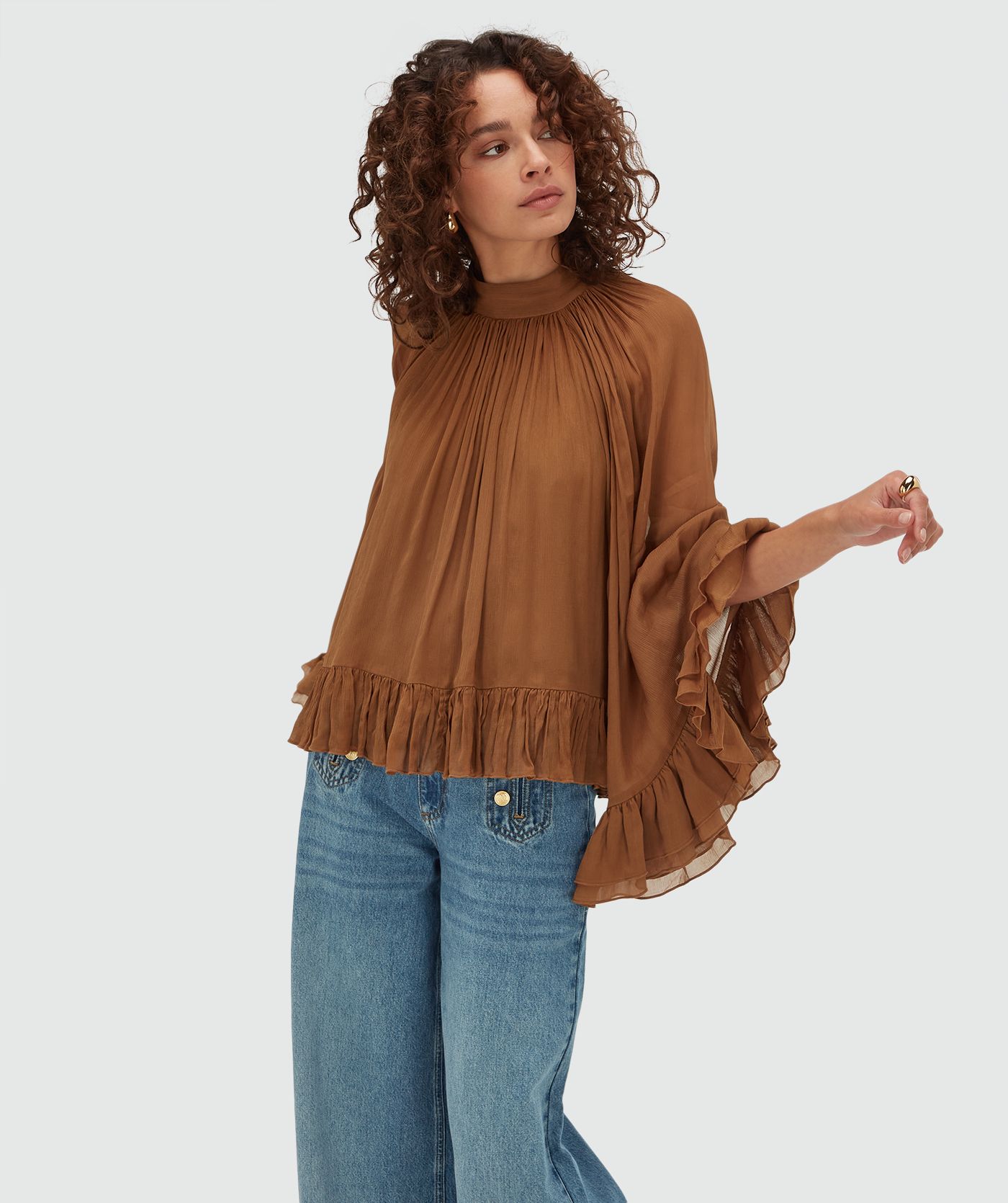 Model draagt een oversized top met ruffle details in de kleur Mocha Brown