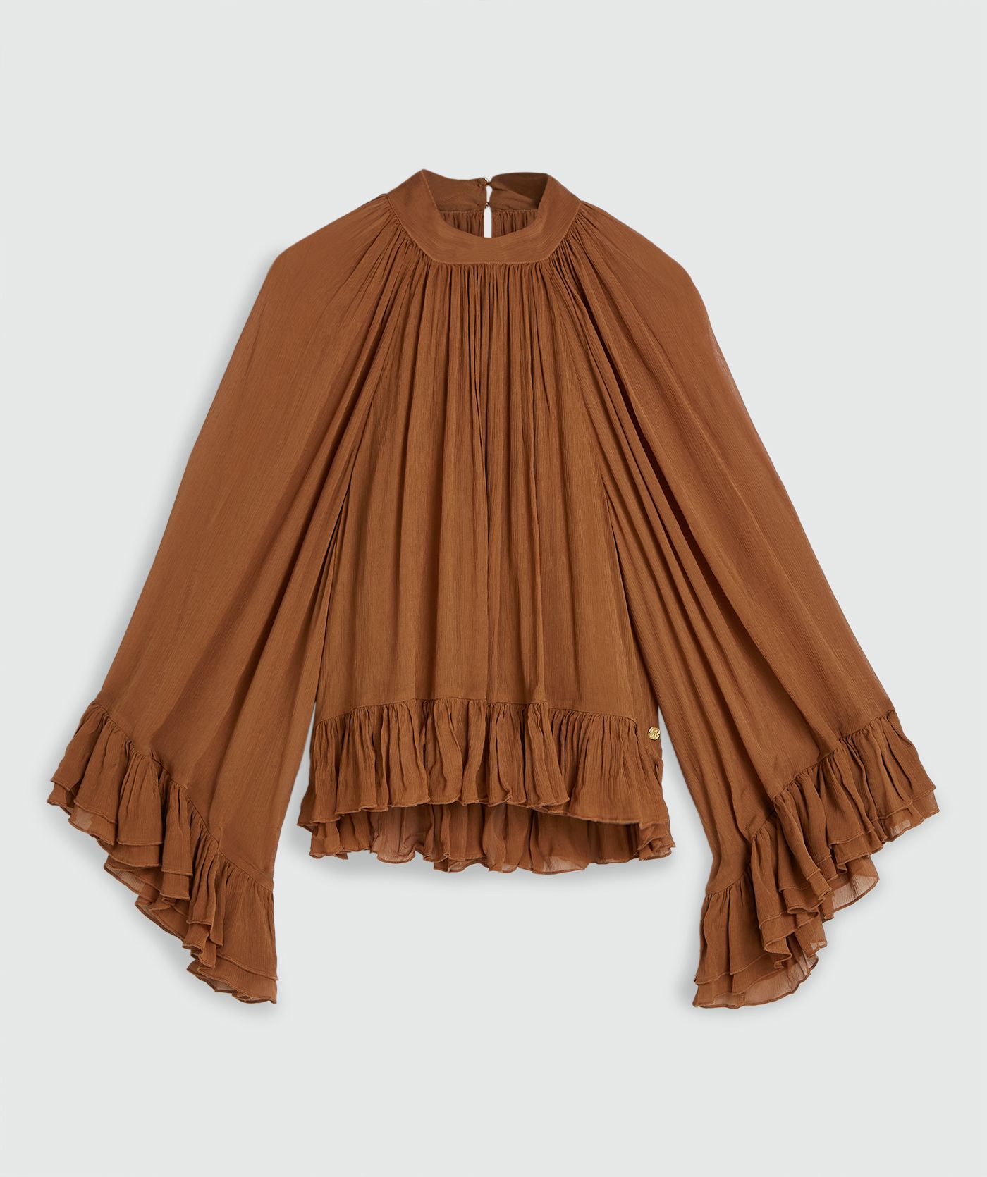 Een oversized top met ruffle details in de kleur Mocha Brown, zonder model, weergegeven op een lichtgrijze achtergrond
