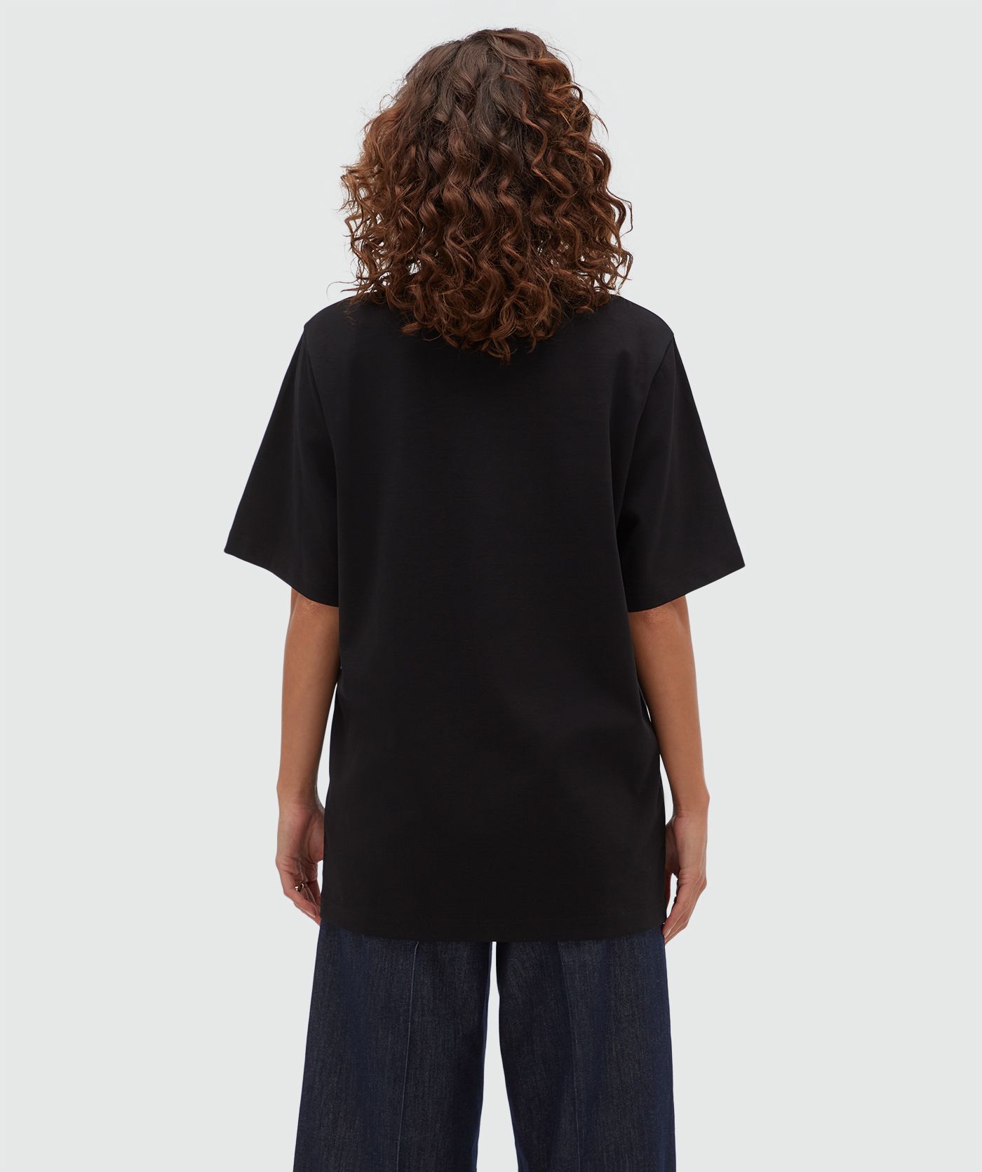 Achteraanzicht van een model in een oversized zwart T-shirt.