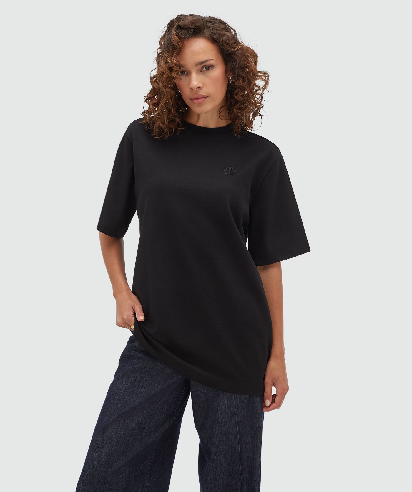 Model draagt een oversized zwart T-shirt.