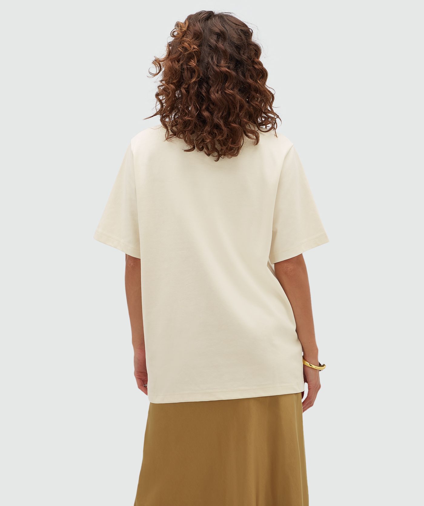 Achteraanzicht van het model met een creme T-shirt. 