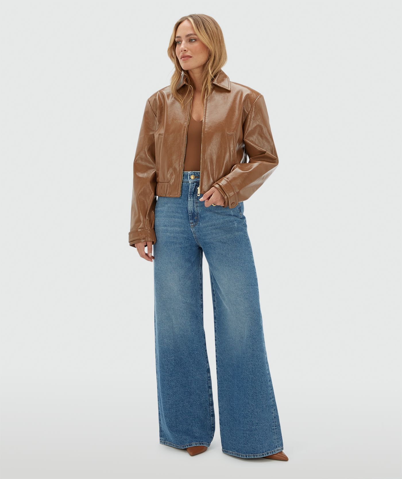 Model draagt een cognac kleurig lak look jasje met rits op een jeans.