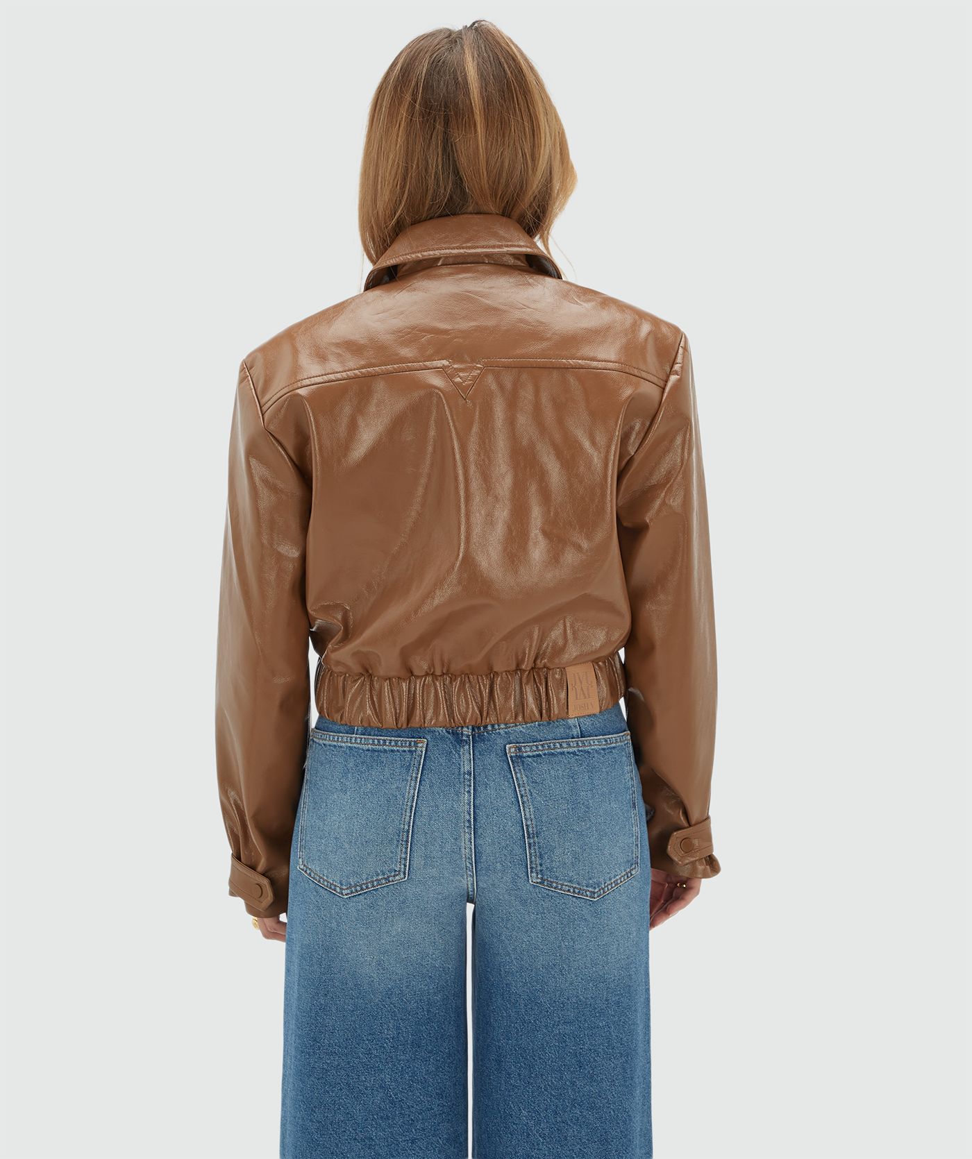 Achteraanzicht van een model in een bruin lak look jasje.