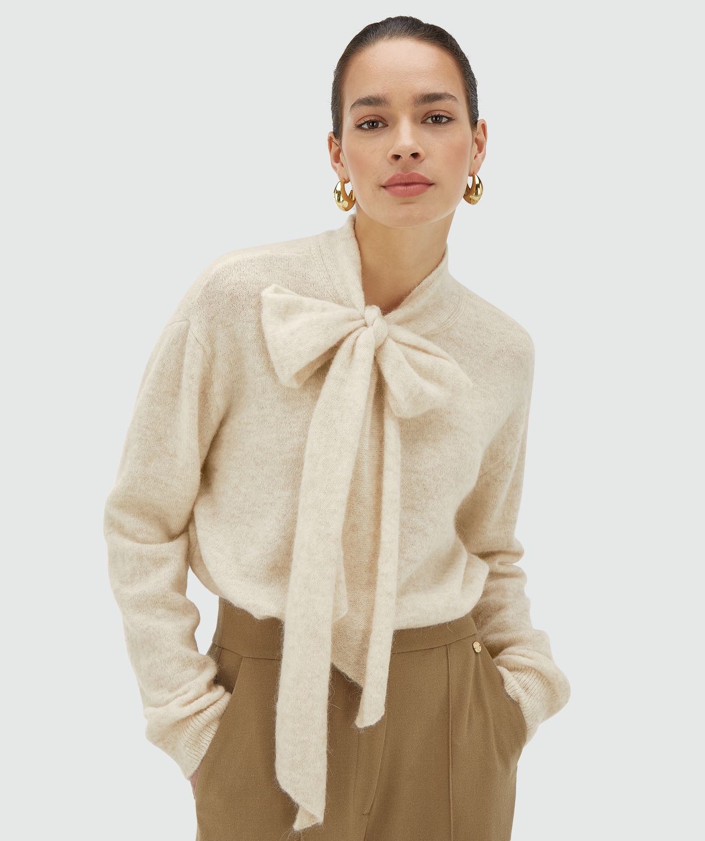 Model draagt een ecru melange regular fit trui met strikdetail bij de hals - Josh V