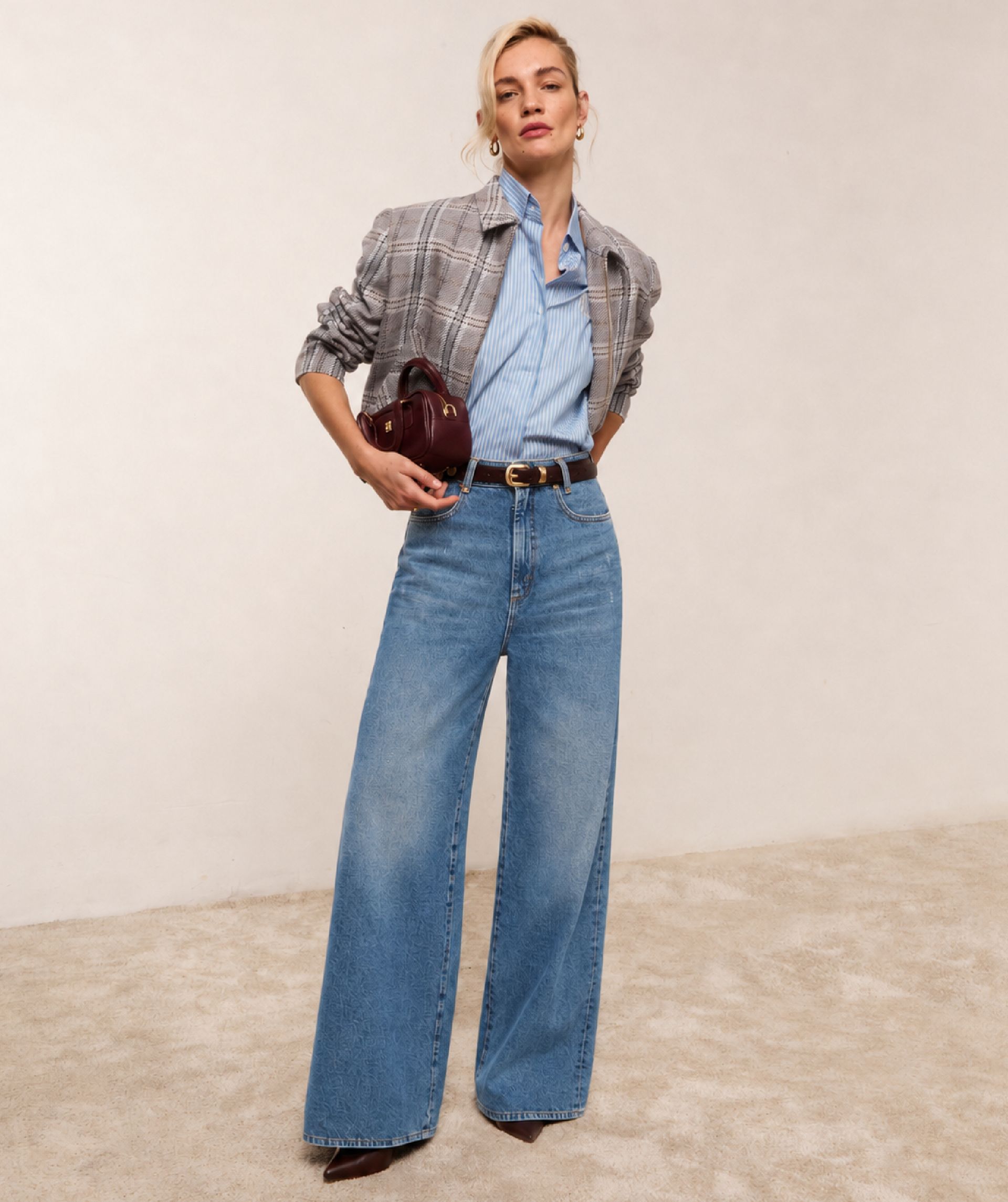 Model draagt het geruite jasje samen met een lichtblauw wit gestreepte blouse op een jeans.