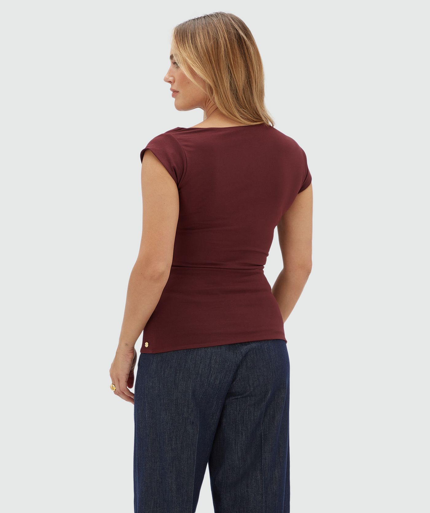 Achteraanzicht van een model in een donkerrode top met korte mouwen.