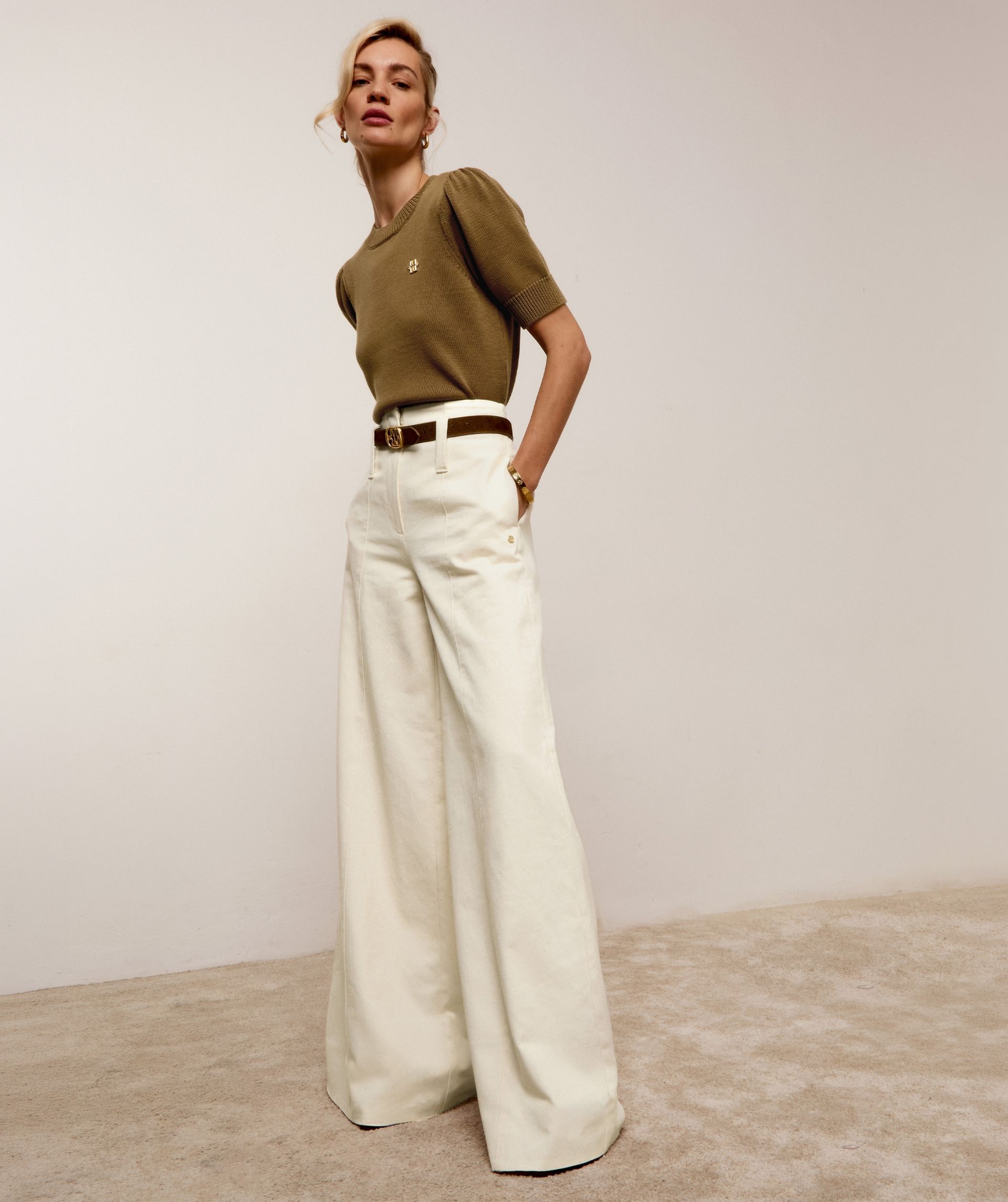 Model draagt een gebroken witte jeans met de bruine pony haar riem.