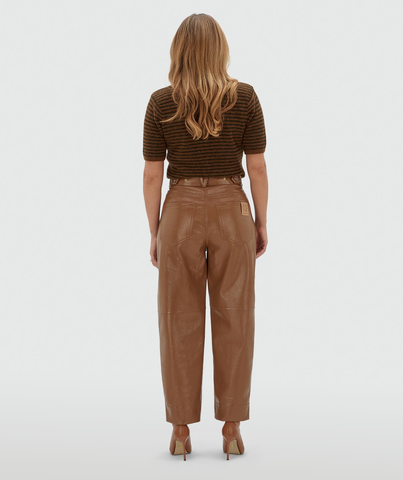 Achteraanzicht van een model in een lichtbruine lak look broek.