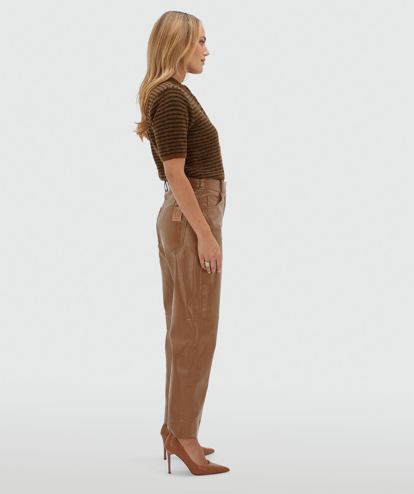 Zijaanzicht van een model in een lichtbruine lak look broek.