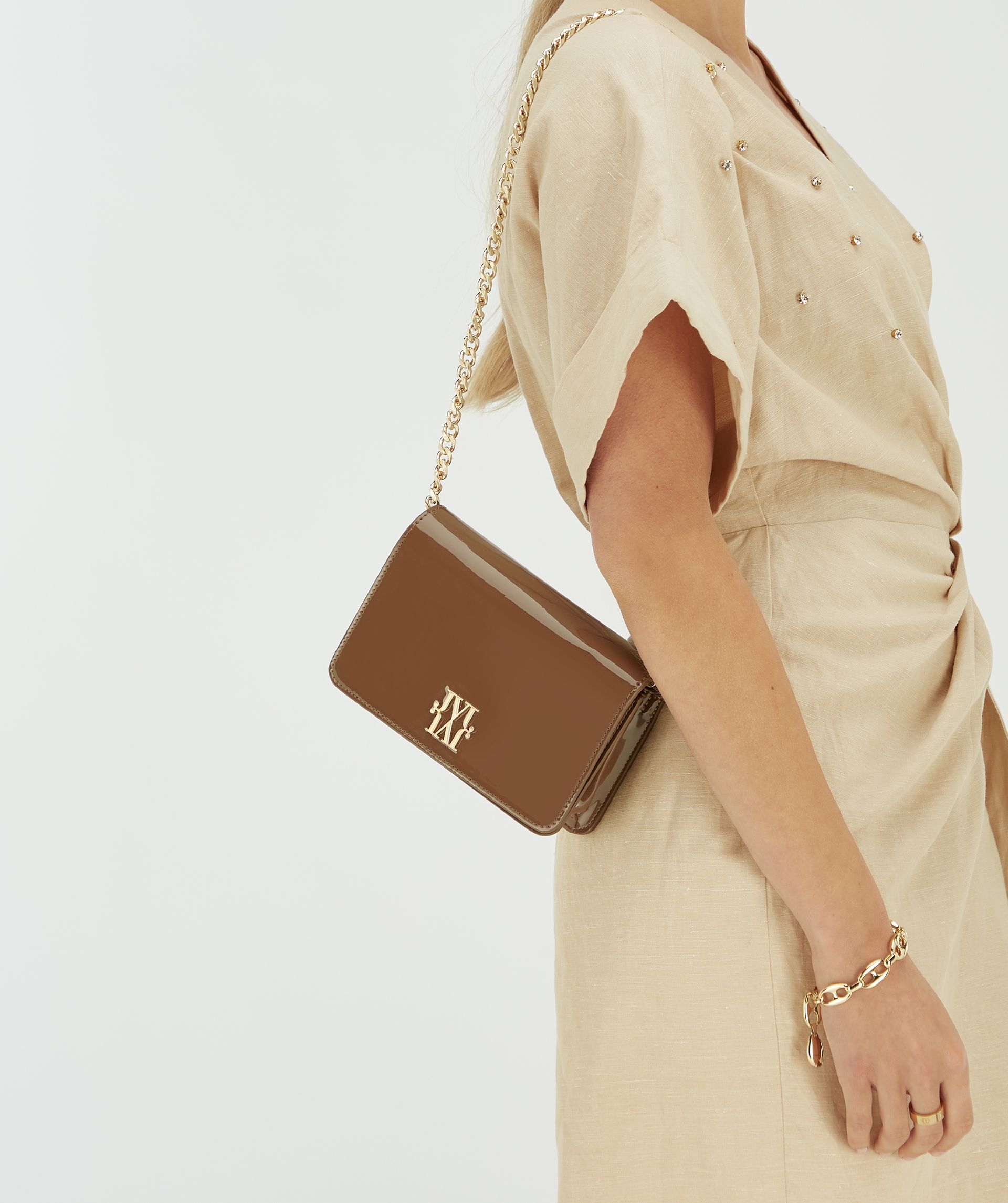 Model draagt de donkerbruine schouder tas met beige overslagjurk.