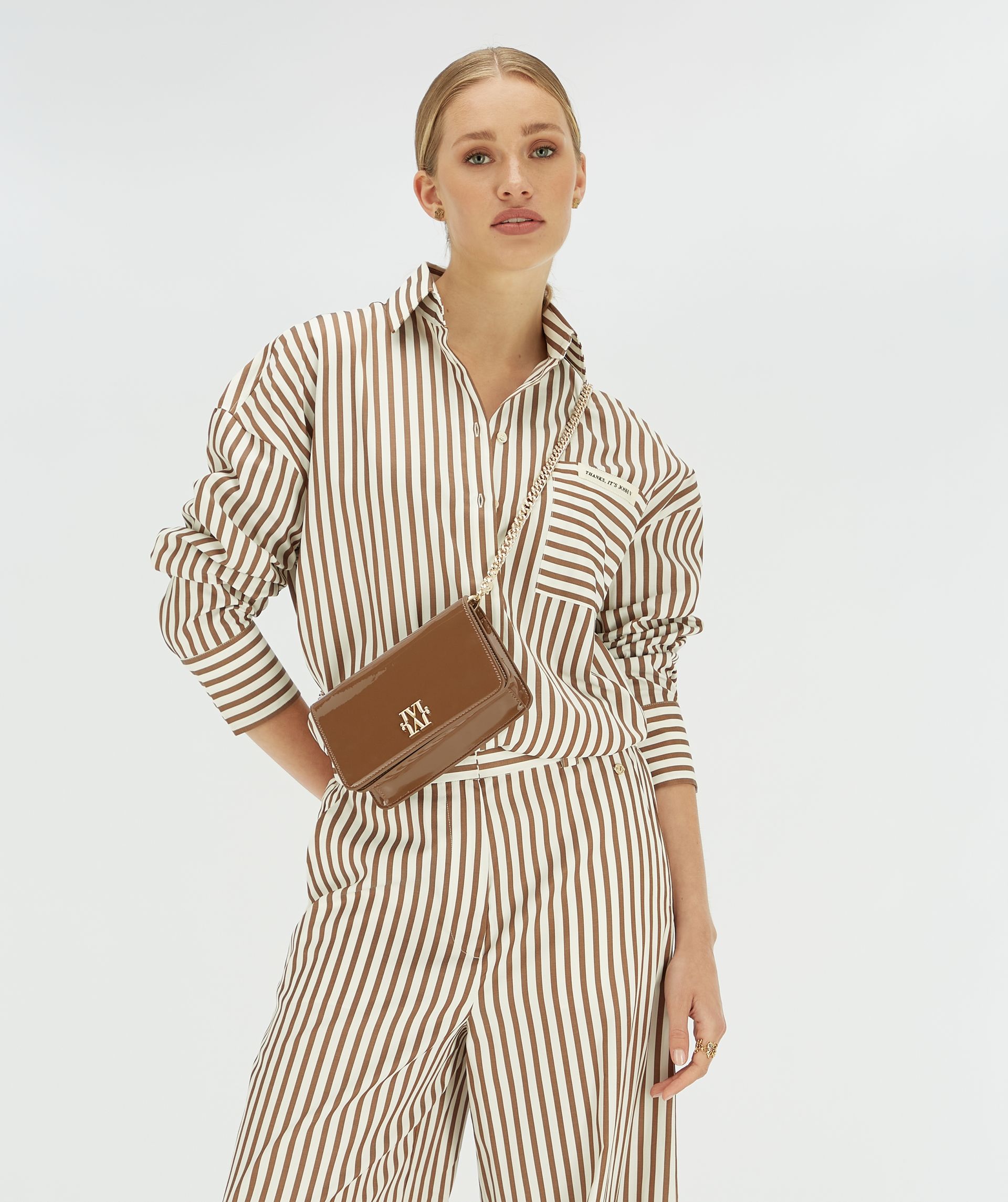 Model draagt donkerbruine tas cross-body met gestreepte blouse.