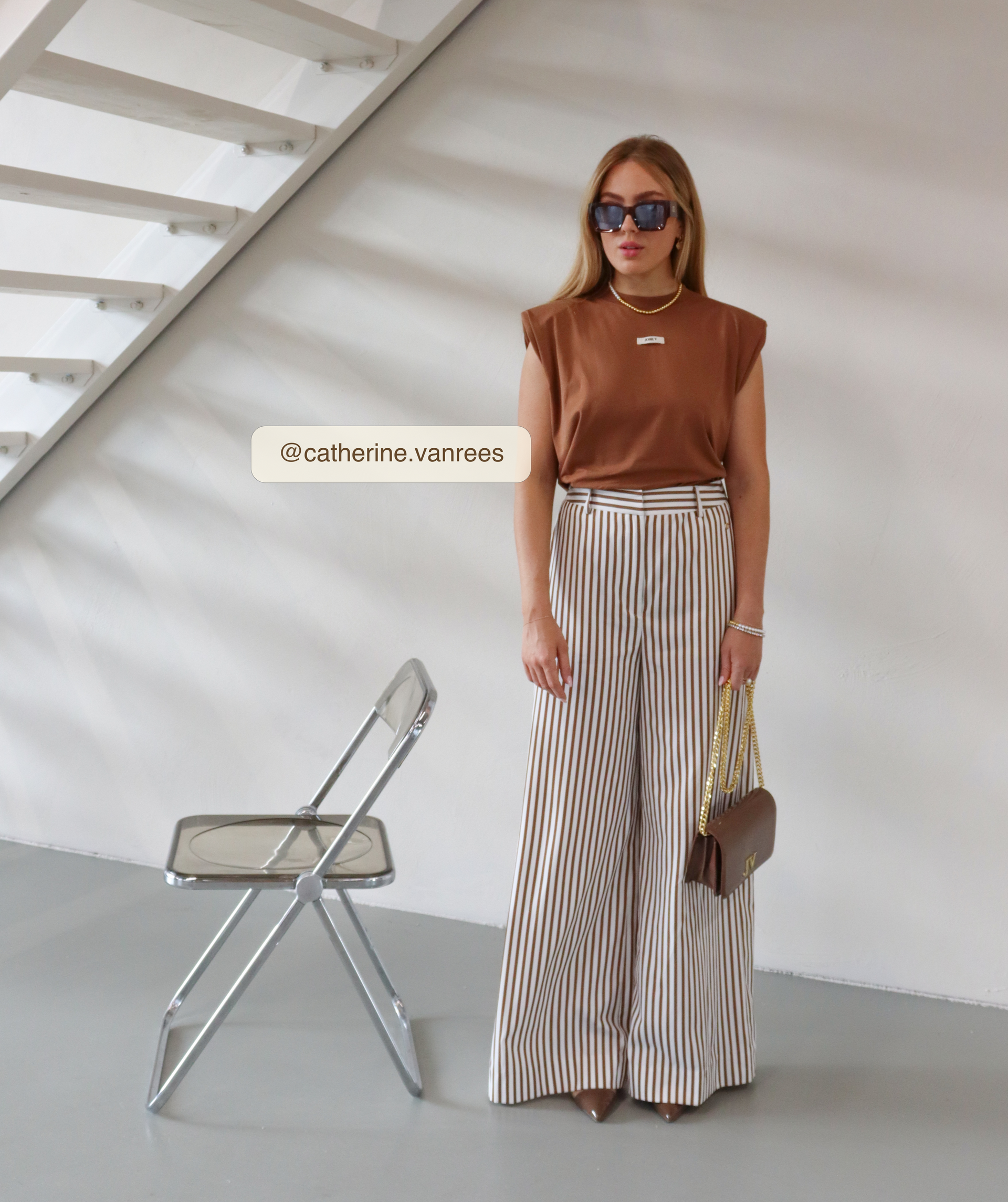 Influencer draagt donkerbruine tas gecombineerd met bruin T-shirt en gestreepte broek.
