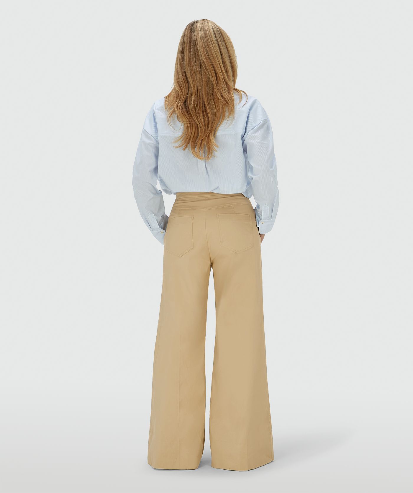 Achteraanzicht van een model in een mid rise wide leg pantalon in de kleur Light Camel, voorzien van verstelbare knopen in de tailleband