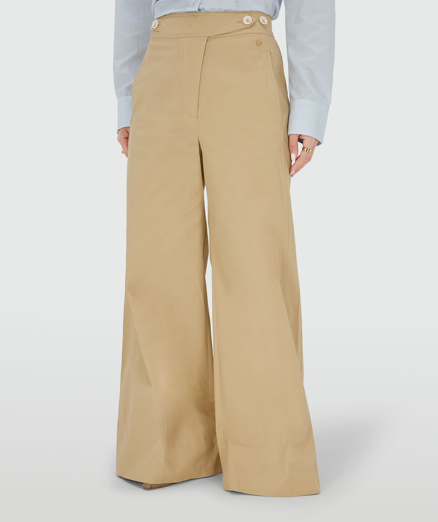 Ingezoomd beeld waarin een model een mid rise wide leg pantalon draagt in de kleur Light Camel, voorzien van verstelbare knopen in de tailleband