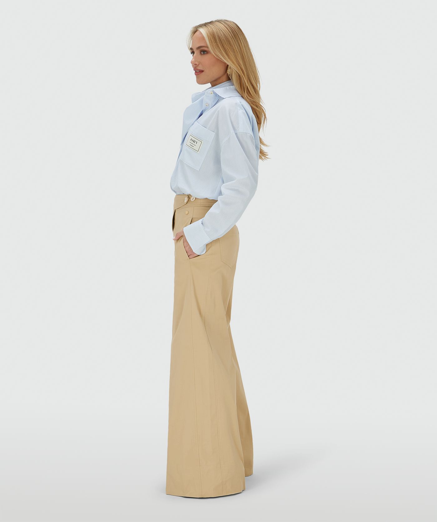 Zijaanzicht van een model in een mid rise wide leg pantalon in de kleur Light Camel, voorzien van verstelbare knopen in de tailleband