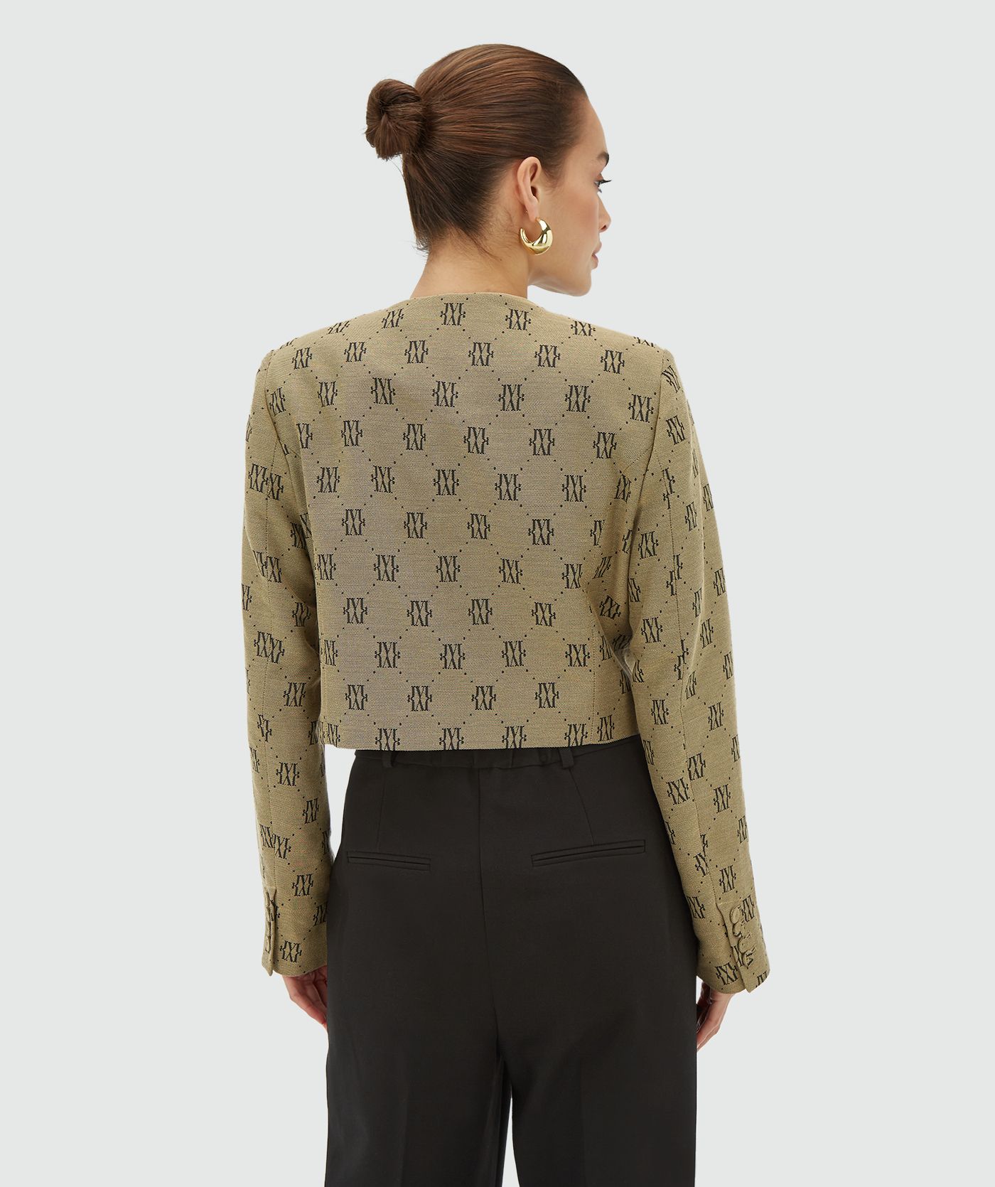 Model draagt een Beige Black blazer met een all-over jacquard geweven logopatroon, schoudervullingen en valt cropped - Josh V