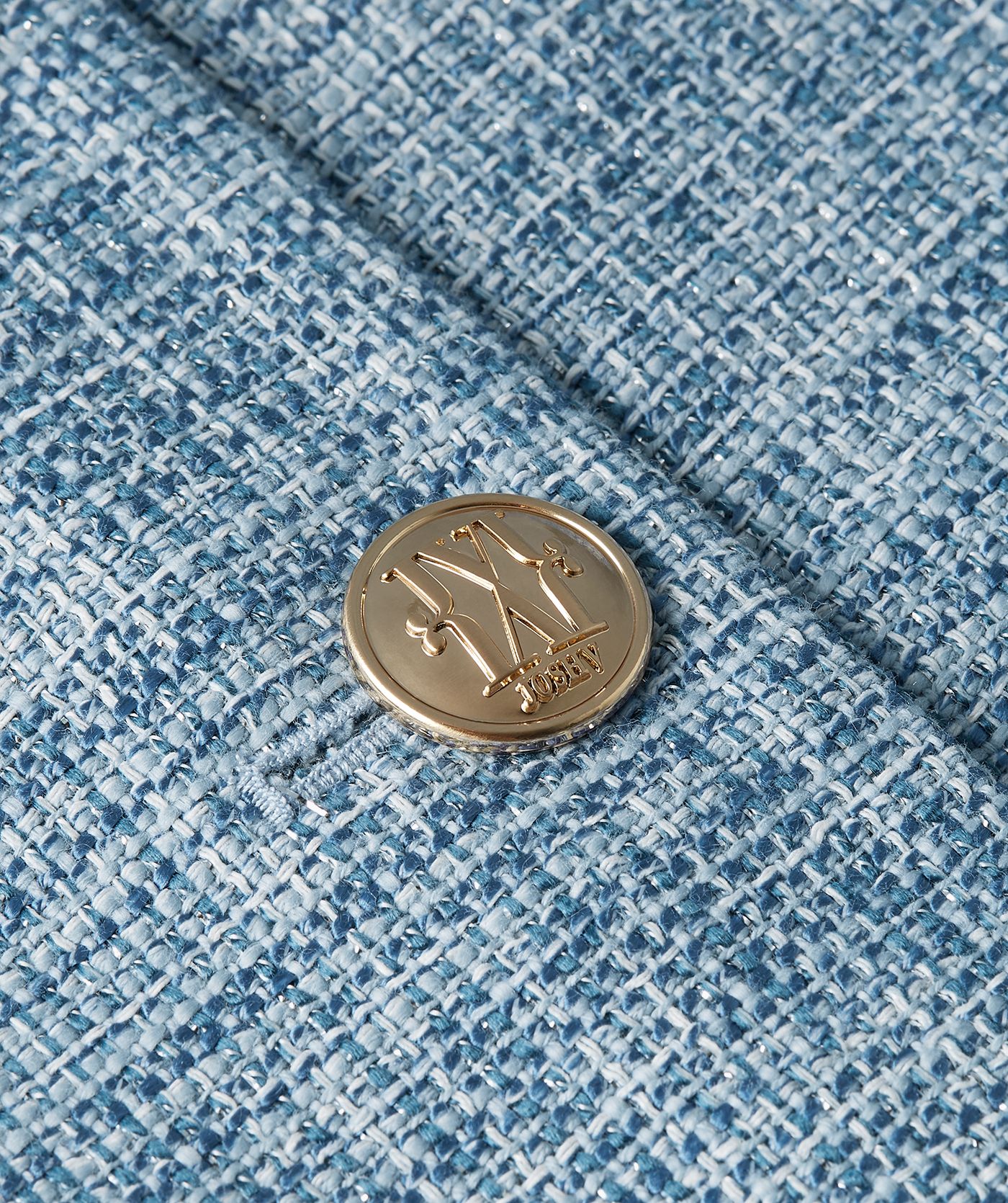 Close-up van de knoopsluiting van een cropped blazer met lurex, uitgevoerd in de kleur Blue Bouclé